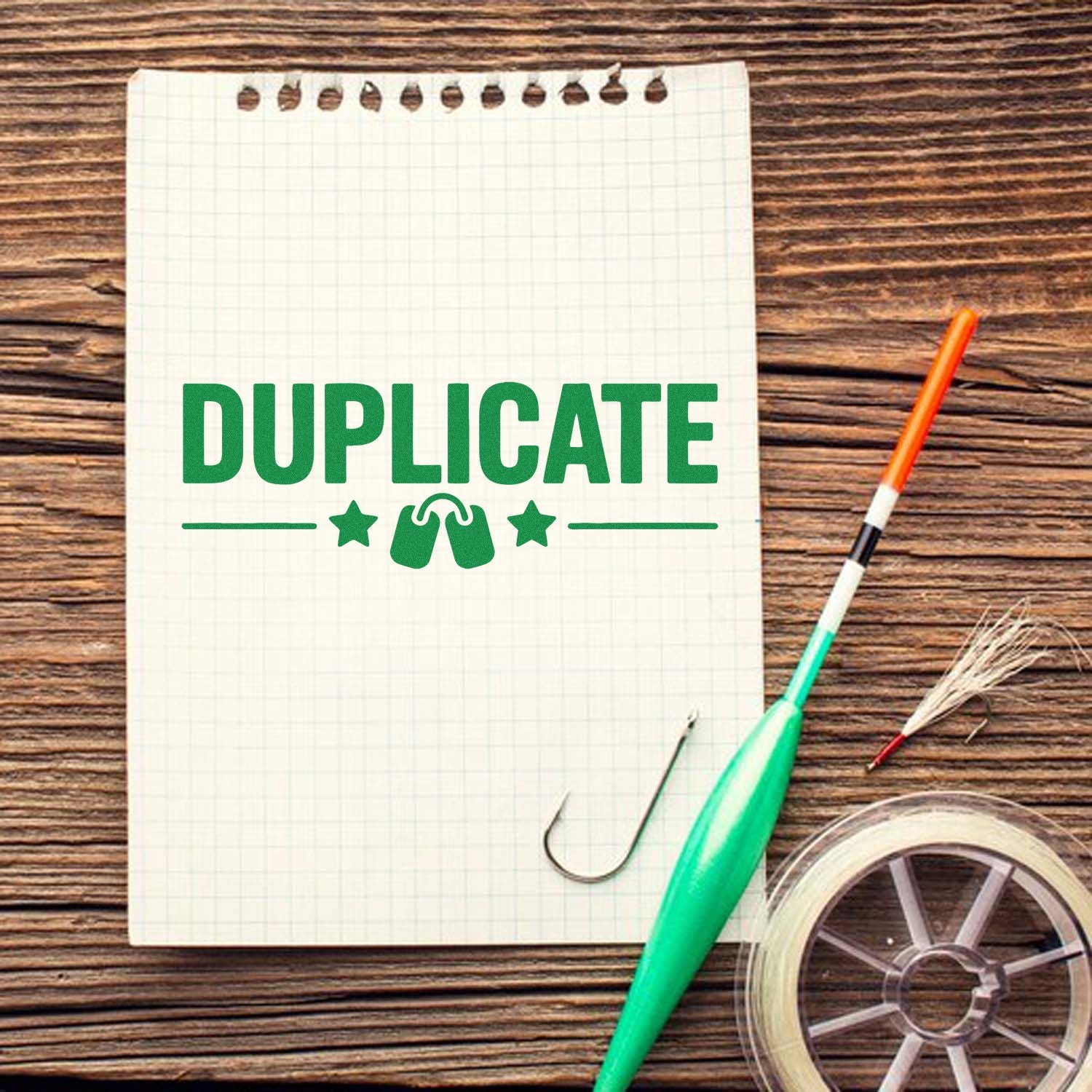 Duplicate rubber stamp design on notepad with crafting tools, paper clip, and tape on rustic wooden desk.