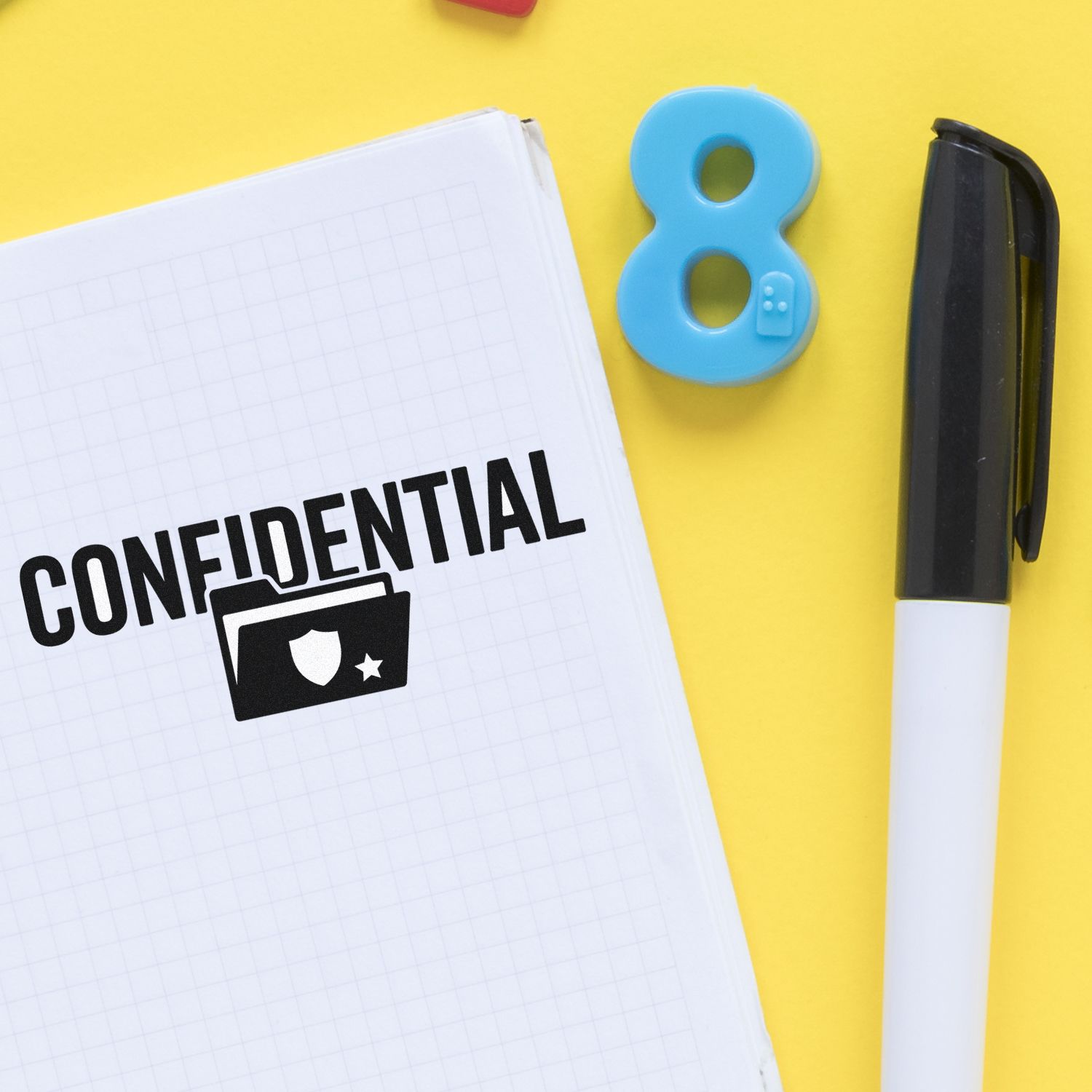 Confidential rubber stamp on notebook with pen and number 8, highlighting secure office document marking.