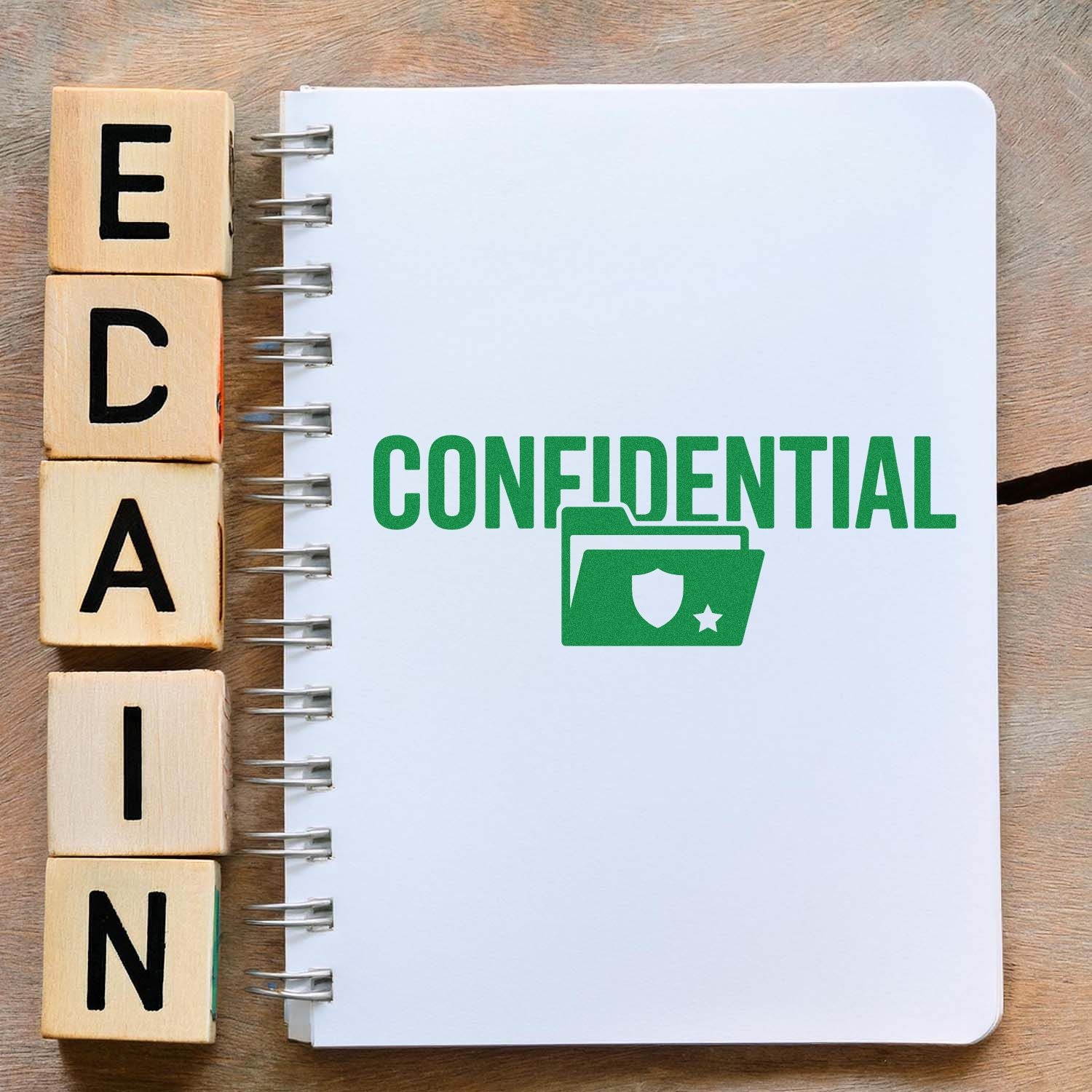Wooden alphabet rubber stamps beside a notebook with a green confidential stamp for document security labeling.