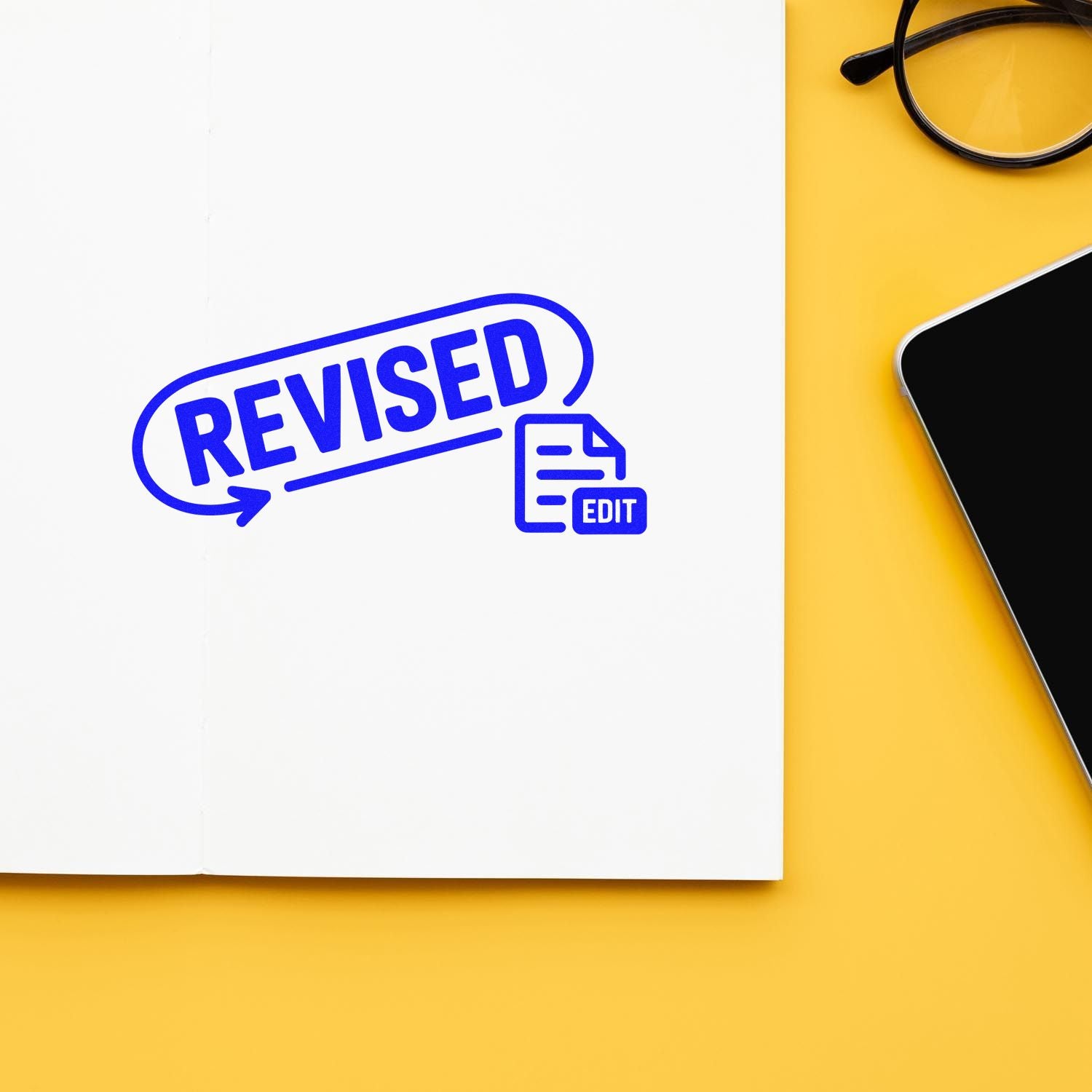 Blue revised rubber stamp on paper with edit icon, for document review, proofreading, and approvals