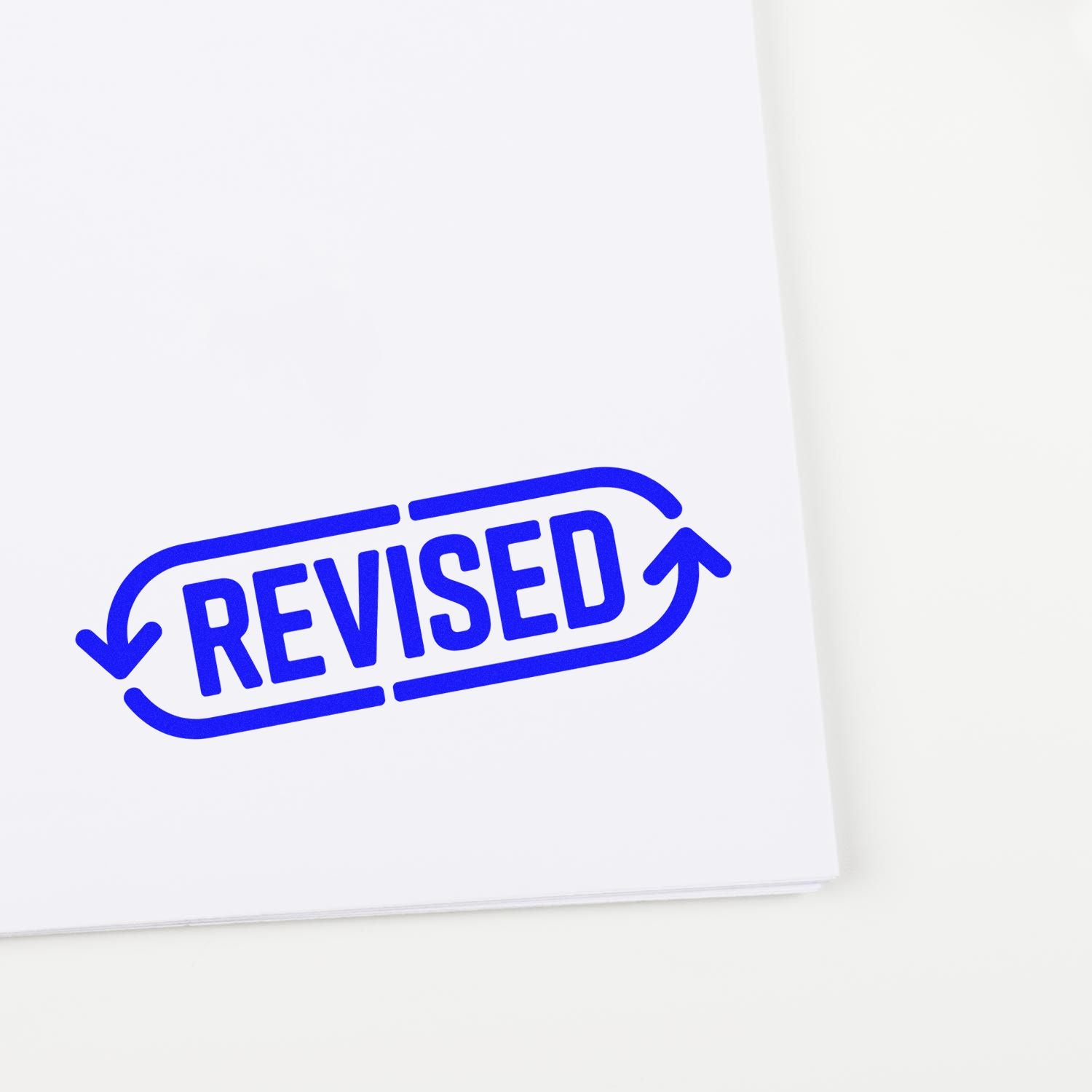 Blue REVISED rubber stamp on document, ideal for marking edited files and office review.
