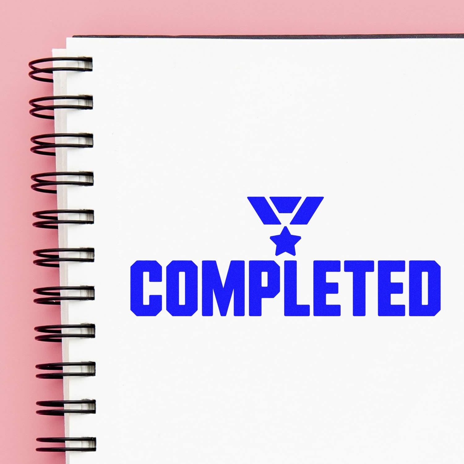 Blue completed rubber stamp imprint on notebook page, signaling task approval and finished status.