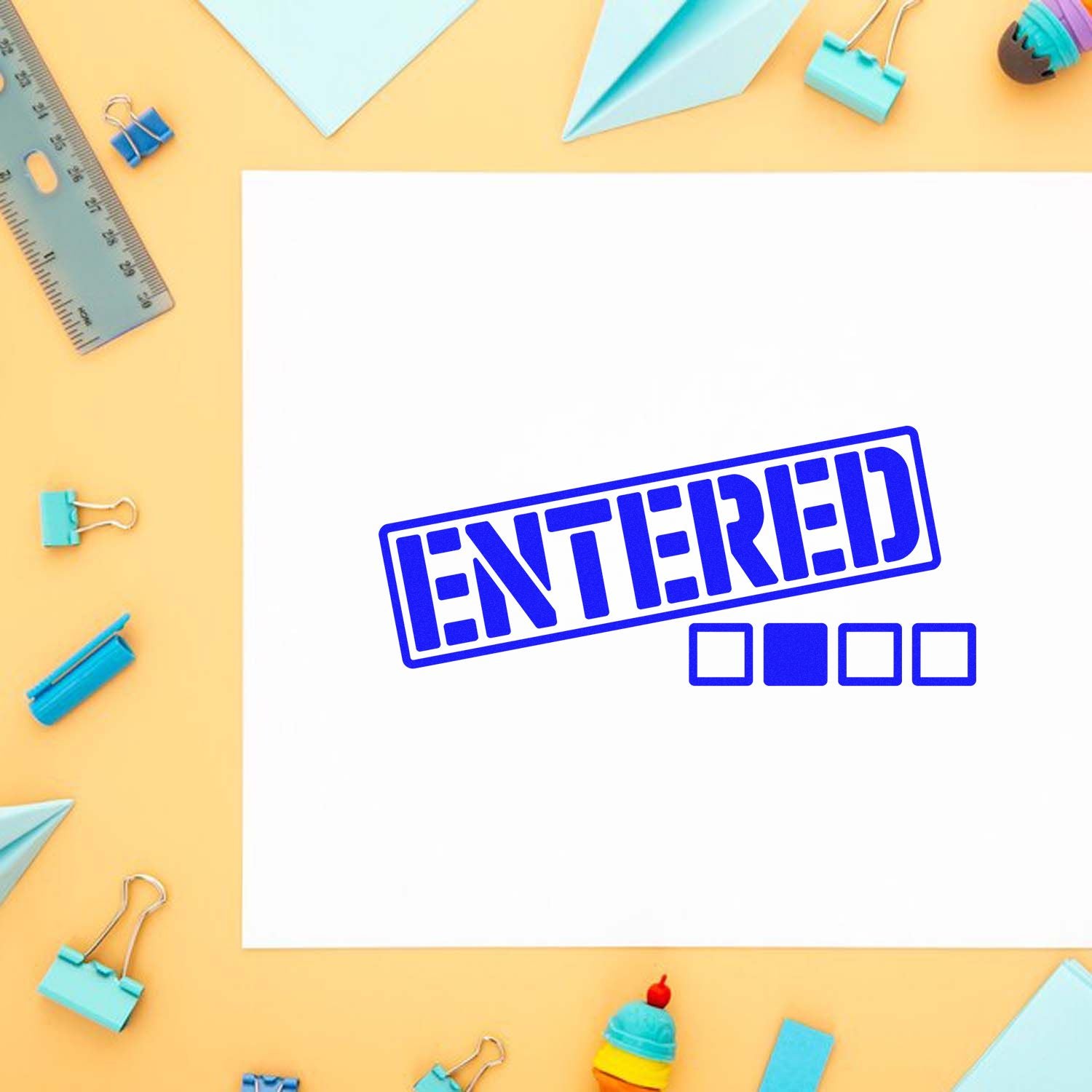 Blue ENTERED rubber stamp on paper for office document processing, surrounded by stationery on a pastel desk.