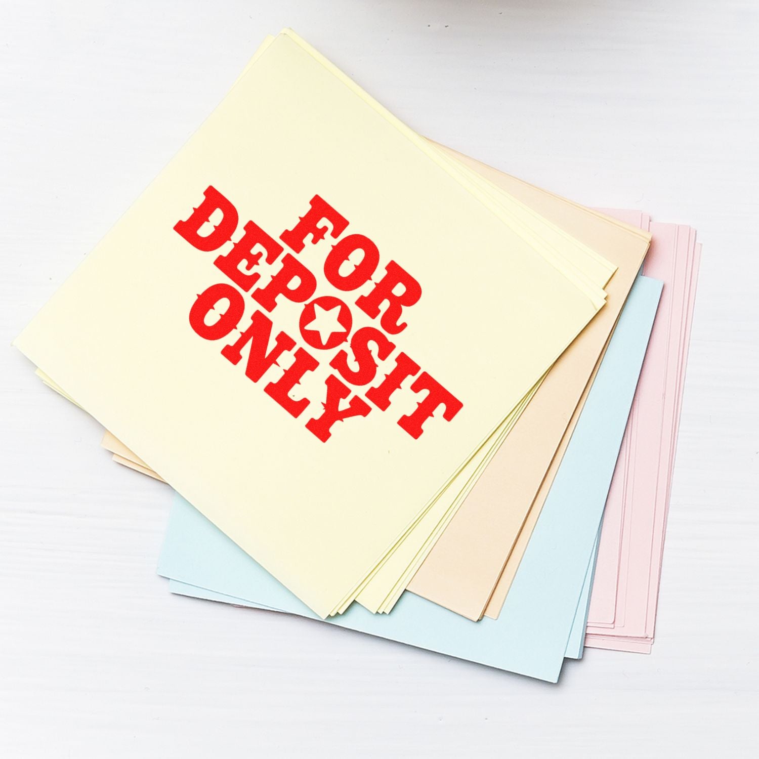 For Deposit Only rubber stamp imprint on pastel paper stack for bank deposit processing