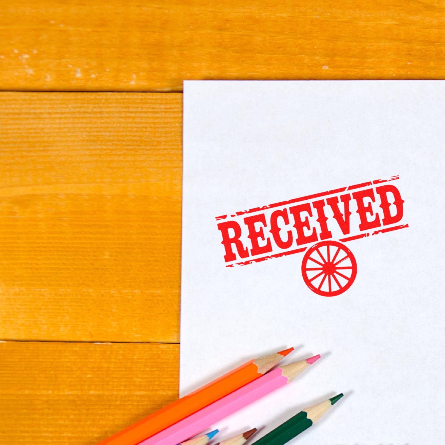Red RECEIVED rubber stamp on paper with colored pencils, ideal for office mail, document approval, and business workflow.