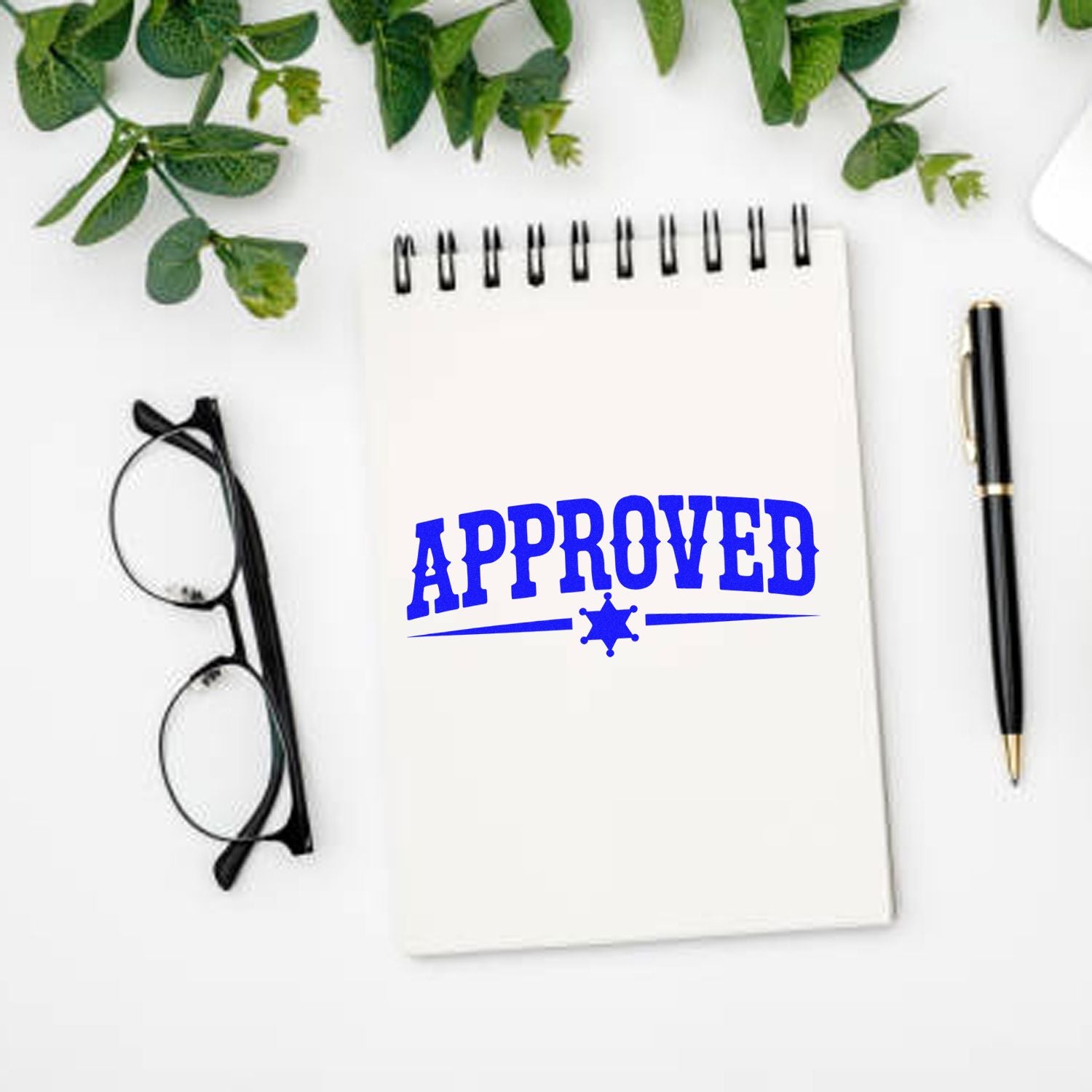 Approved rubber stamp on notebook for office paperwork, with pen and glasses on a clean desk.
