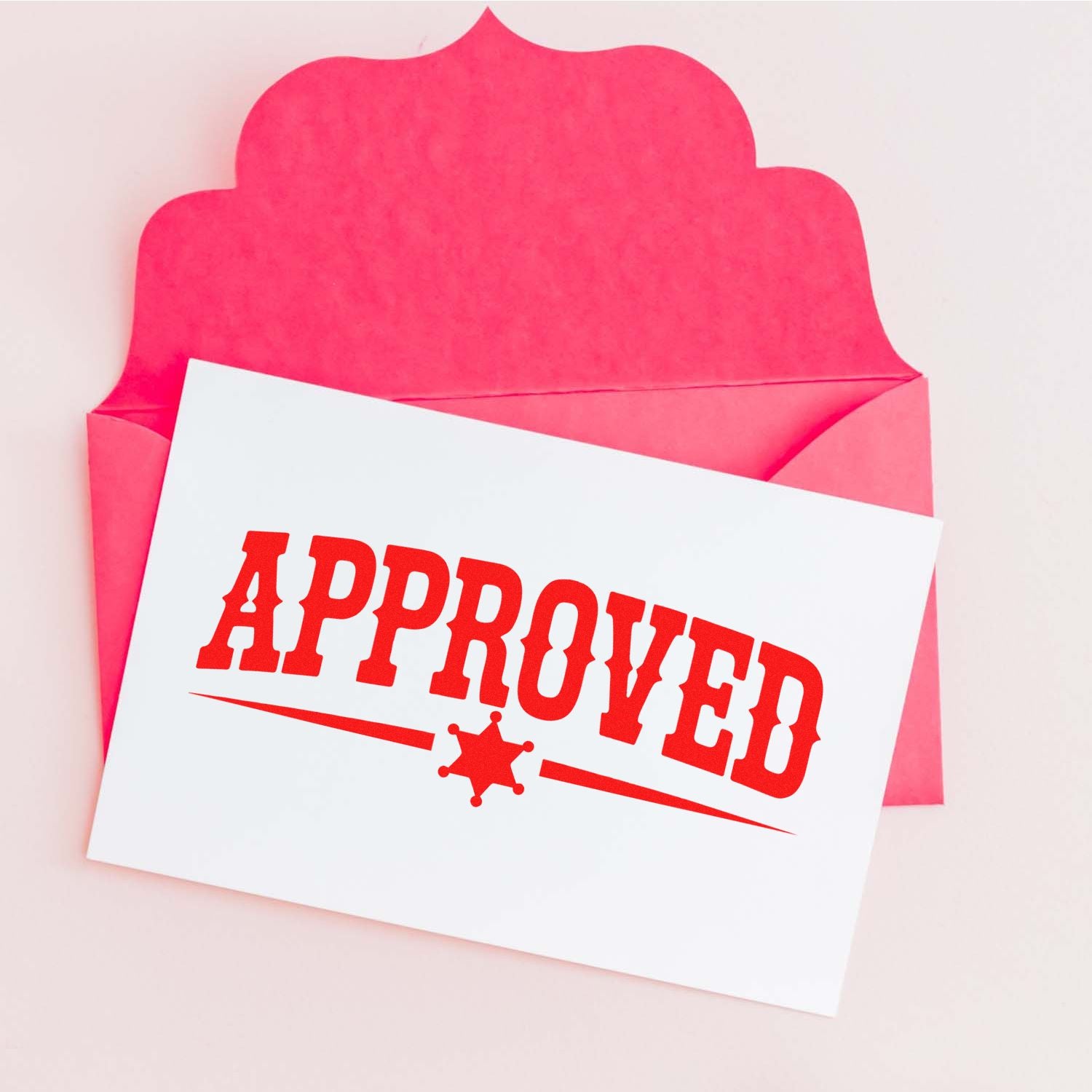 Approved rubber stamp on white card inside a pink envelope for business mail and office document approval.