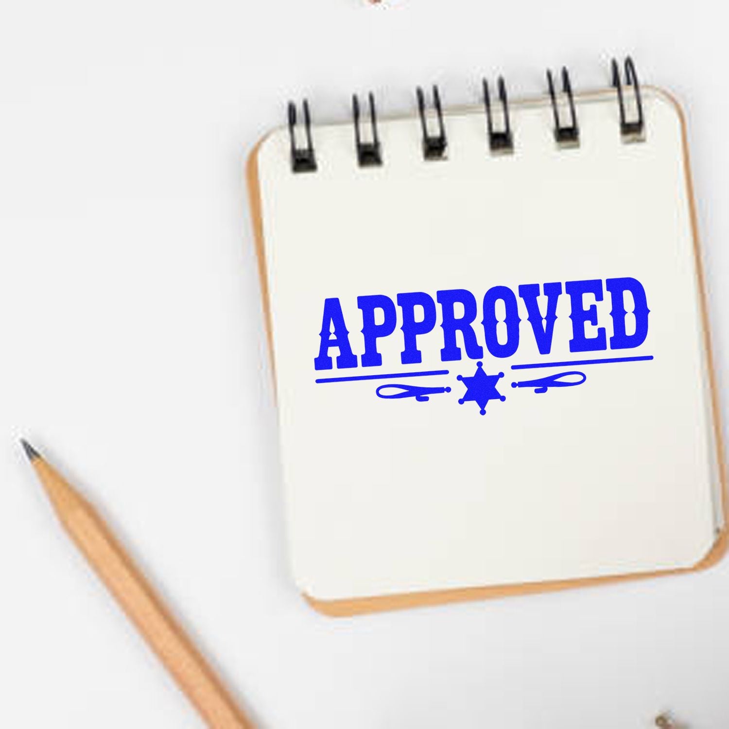 Blue APPROVED rubber stamp on notebook page with pencil, ideal for office approval and document marking.