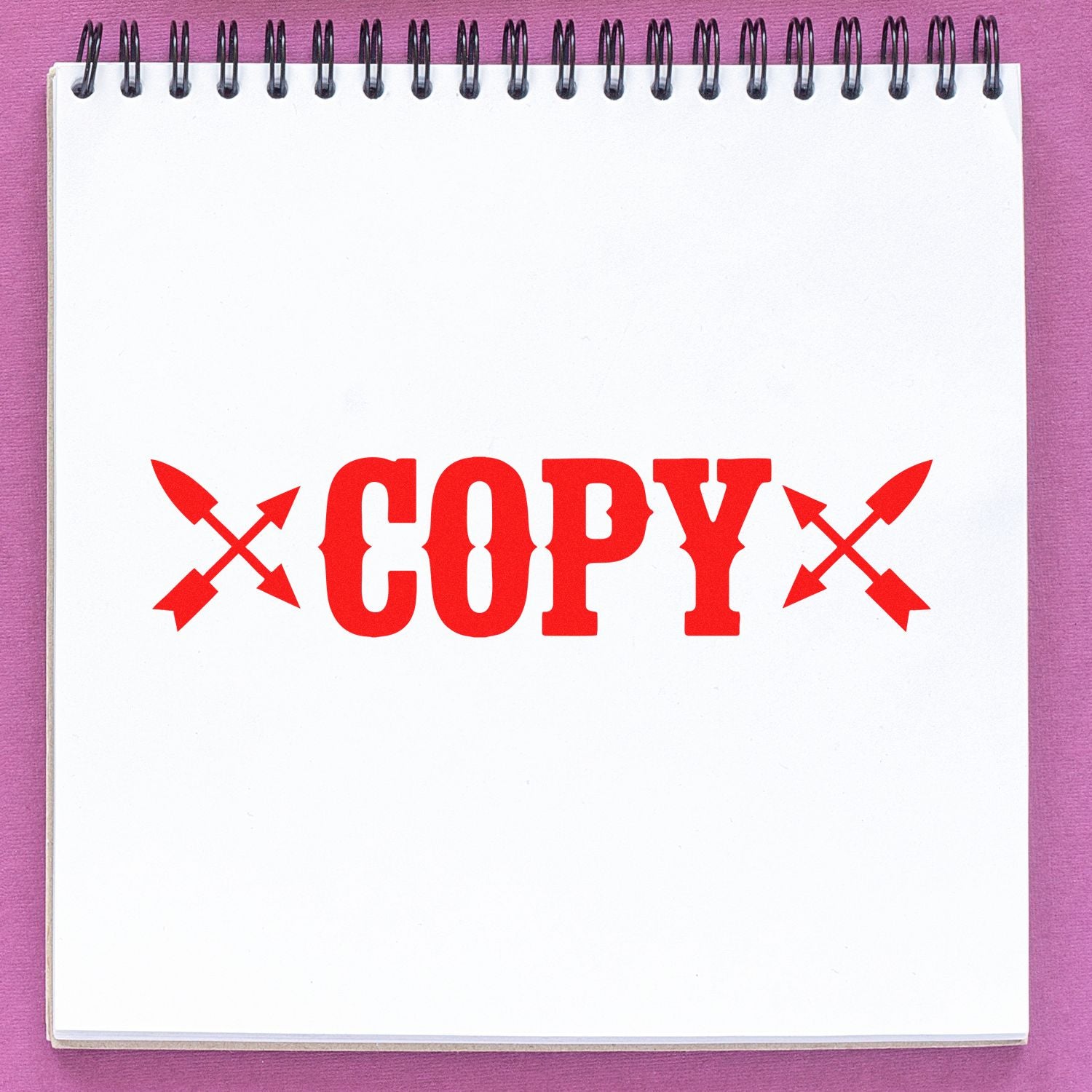 Red COPY rubber stamp with crossed arrows on a blank spiral notebook page