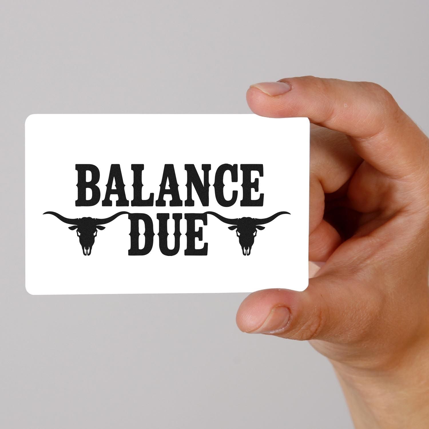 Balance Due custom rubber stamp design with longhorn skulls, held in hand