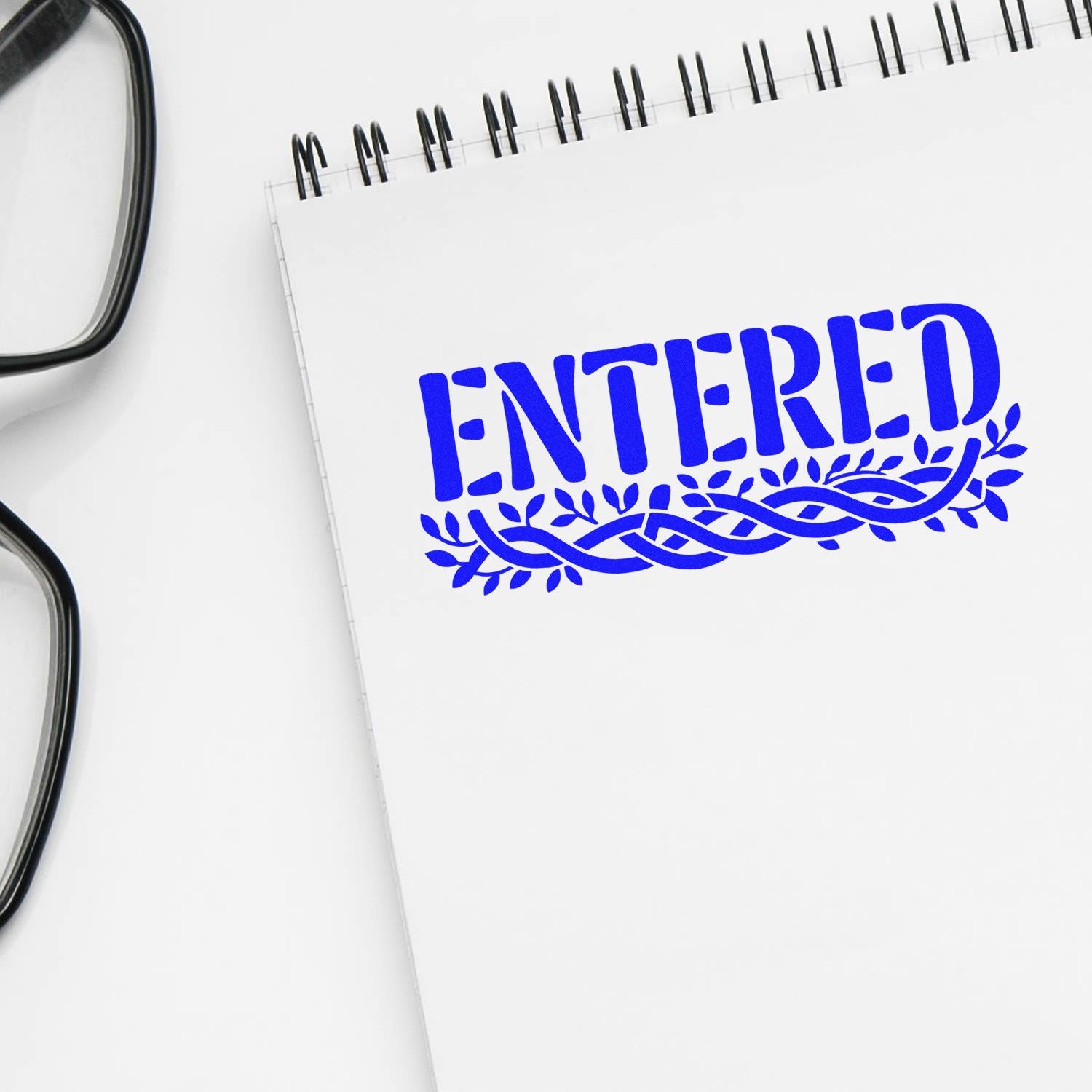 Blue ENTERED rubber stamp impression on notebook, ideal for office paperwork and document approval.