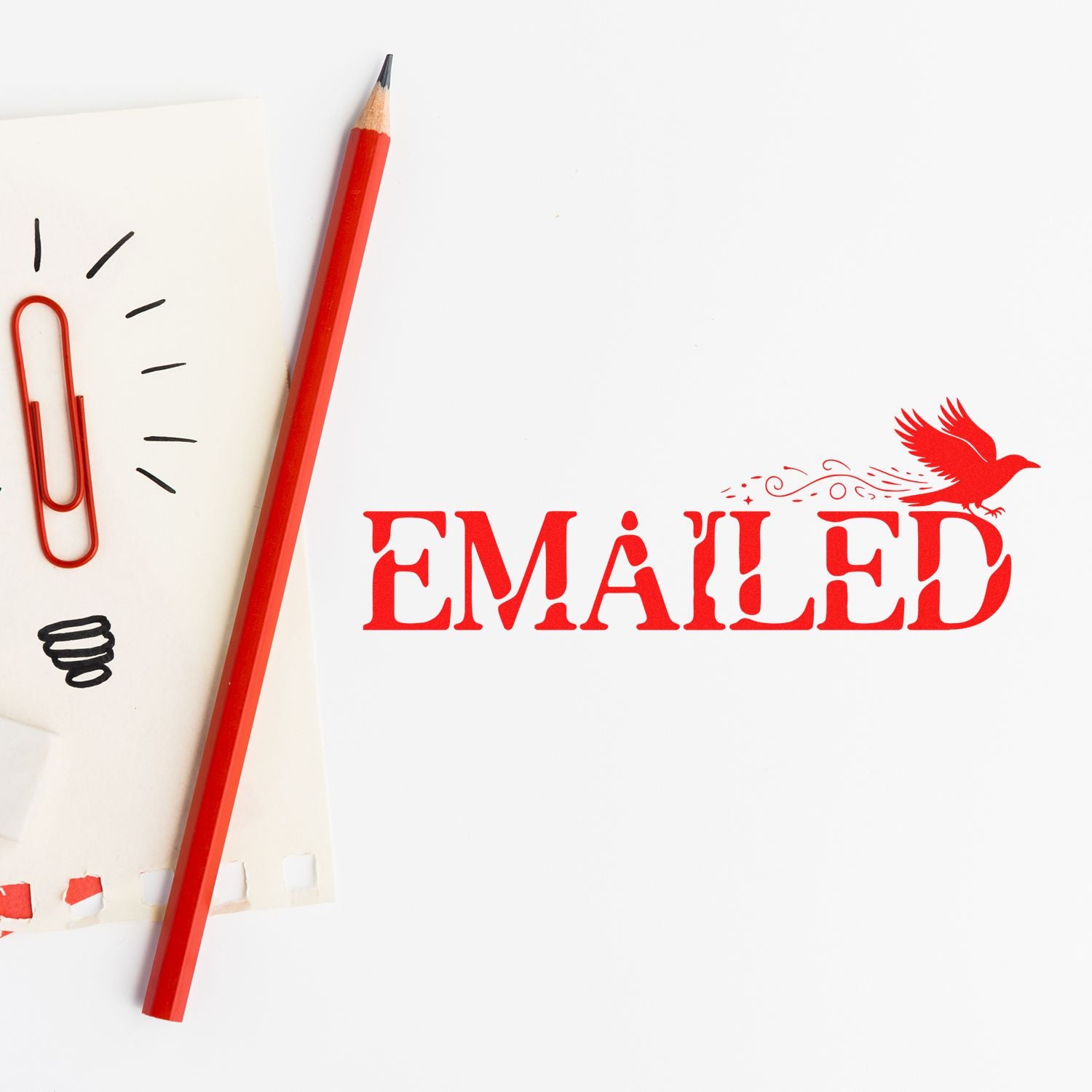 Red EMAILED rubber stamp on paper with pencil and paperclip, marking a document as sent in an office workflow.
