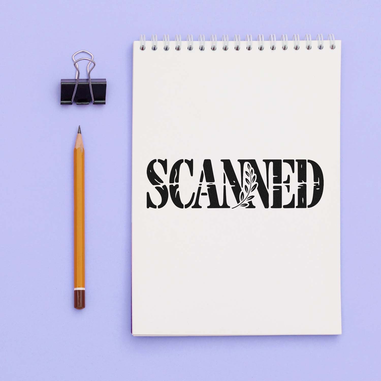 Rubber stamp impression reading SCANNED on a notebook page, ideal for office document labeling and archive organization.