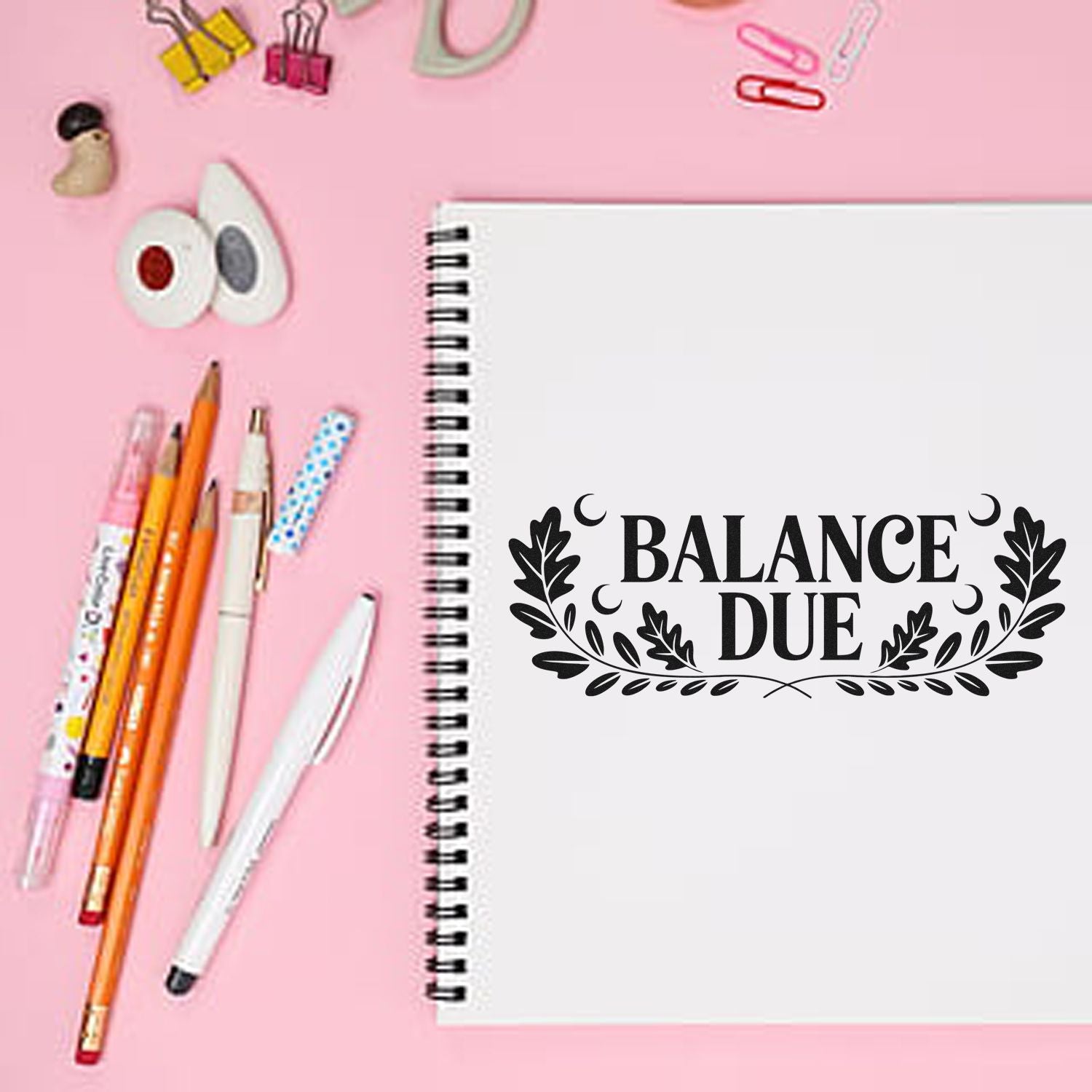 Balance Due rubber stamp on notebook for invoices, bookkeeping, and office organization on a pink desk with pens.