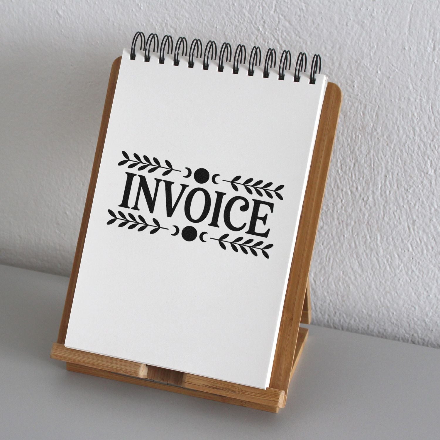 Custom invoice rubber stamp impression on notepad, decorative leaf border design for business billing, bookkeeping, and office use.