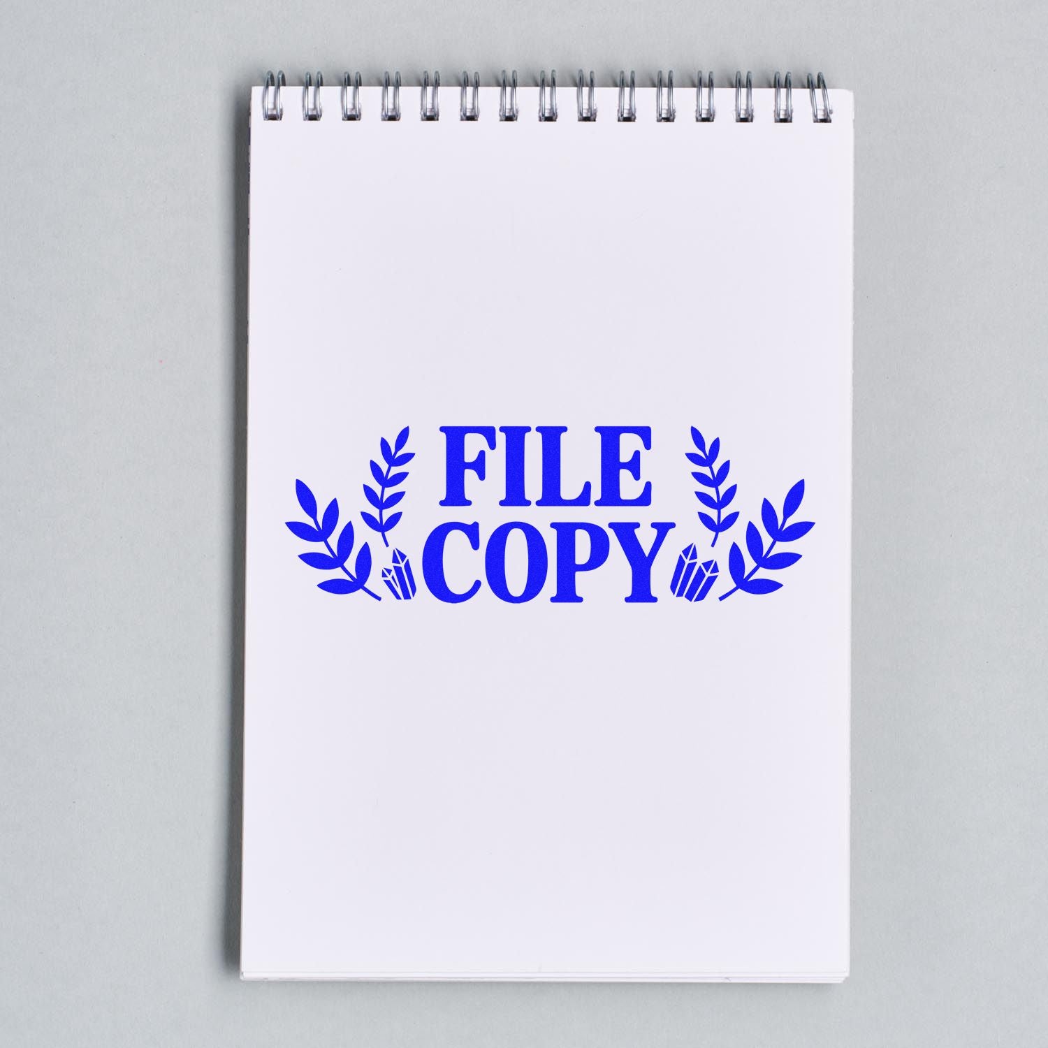 FILE COPY rubber stamp design with laurel leaves on a spiral notebook page for office document labeling.