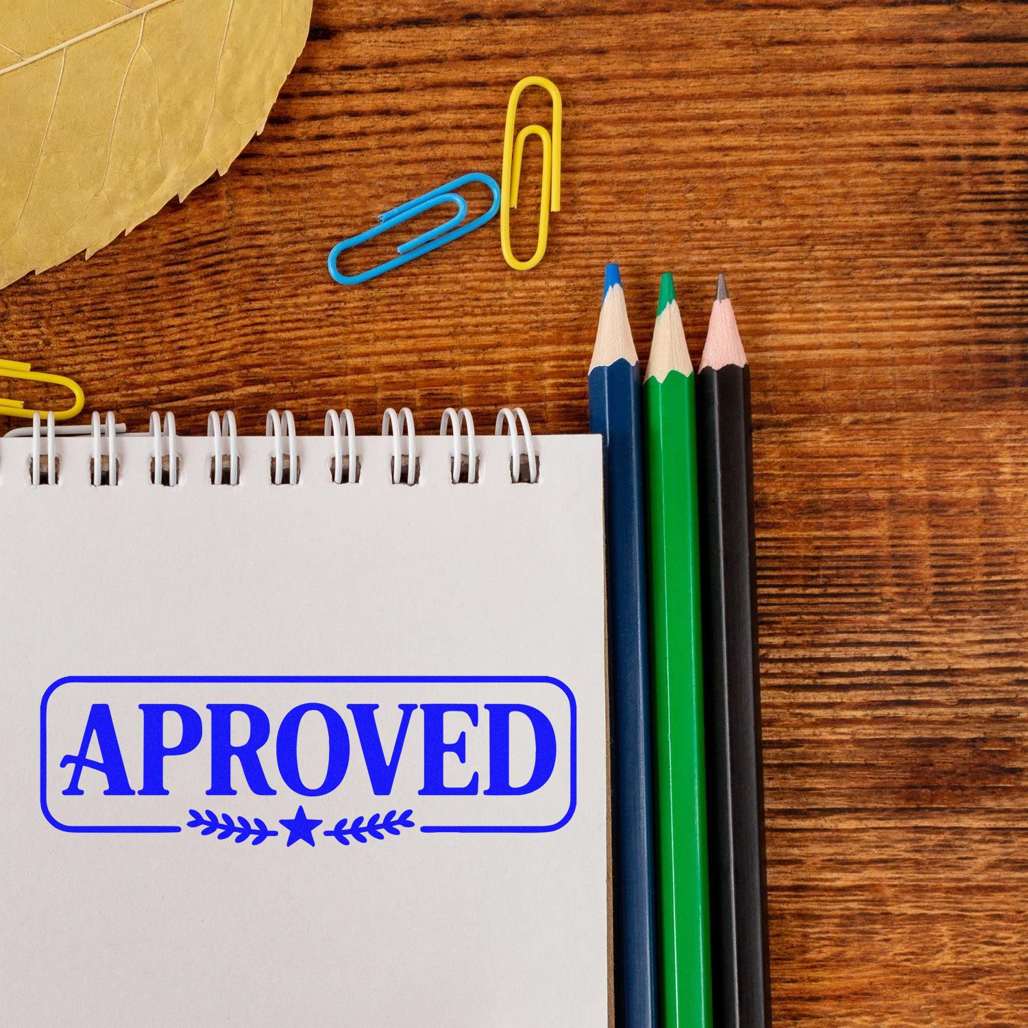 Approved rubber stamp on a notebook with office supplies on a wooden desk, ideal for document approval and business use.
