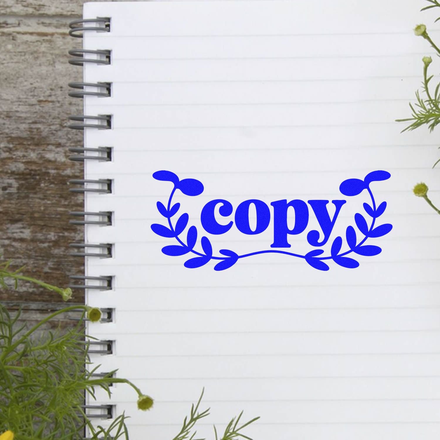 Blue copy rubber stamp design with leafy floral wreath on lined notebook paper