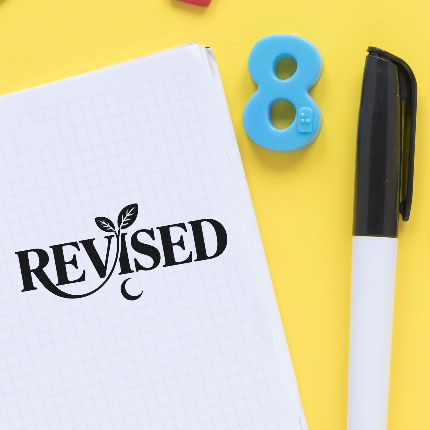 Revised rubber stamp on notebook page with pen, marking edited documents for office review.