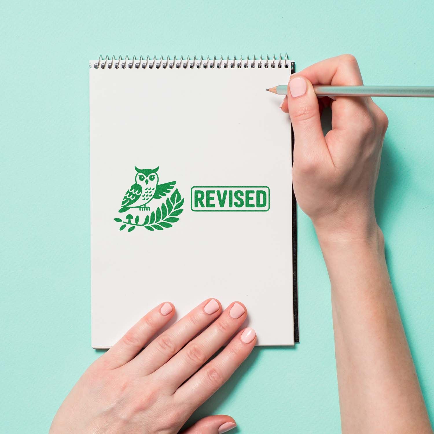 Revised rubber stamp with owl icon on notebook page for editorial review or teacher marking