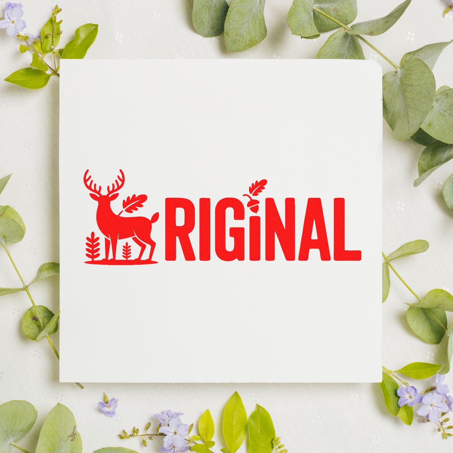 Red original deer rubber stamp design with leaf accents on a white card, framed by greenery and flowers.