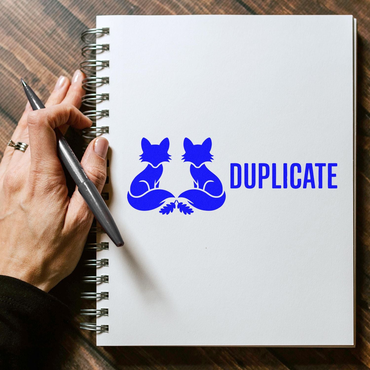 Blue duplicate rubber stamp imprint with mirrored foxes on a notebook page, ideal for office copy labeling.