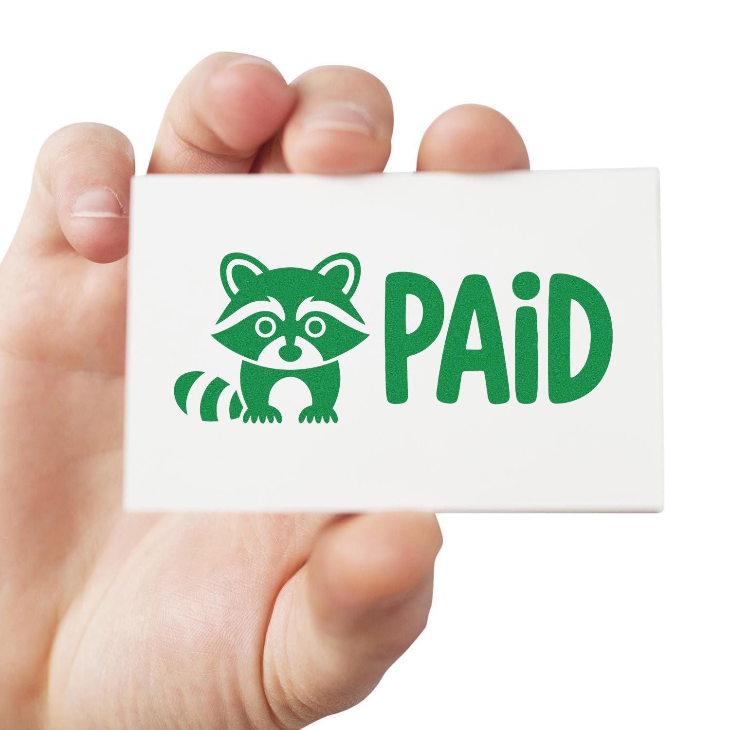 Hand holding custom rubber stamp with green raccoon and PAID text, ideal for office and business document marking.