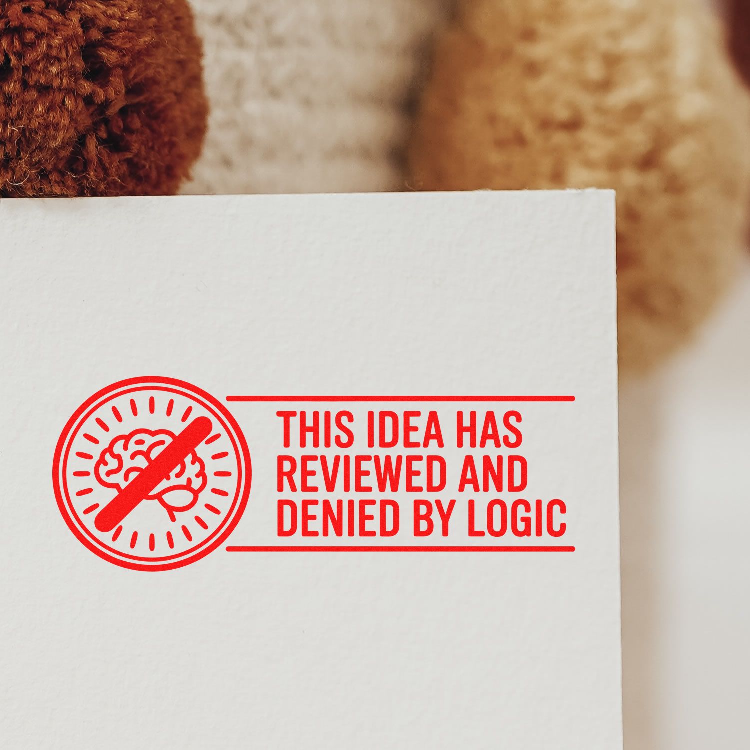 Humorous rubber stamp design with crossed-out brain icon and text: This idea has been reviewed and denied by logic.