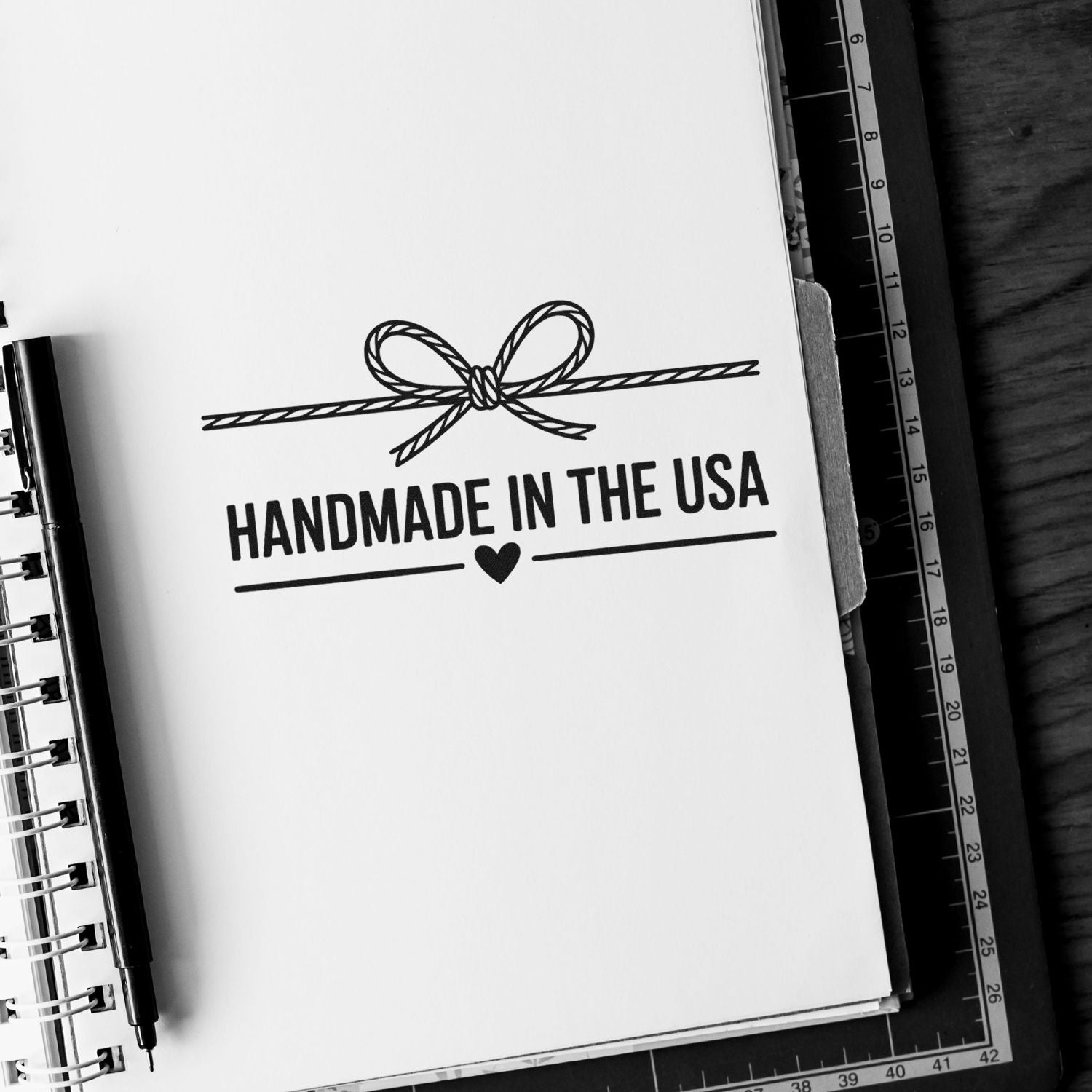 Handmade in the USA rubber stamp design with bow and heart, ideal for handmade product packaging and branding.