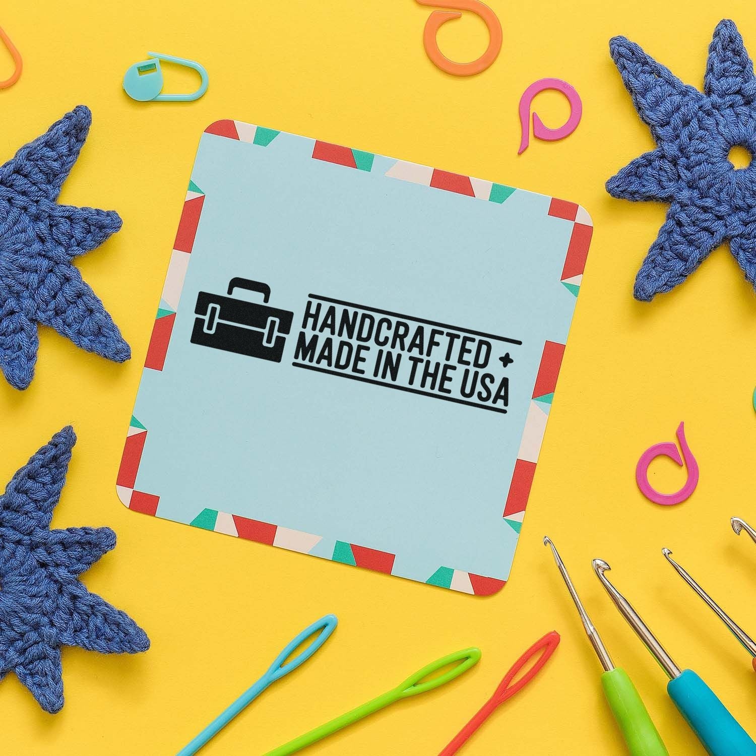Handcrafted Made in the USA rubber stamp design for handmade product packaging, surrounded by crochet hooks and craft supplies.