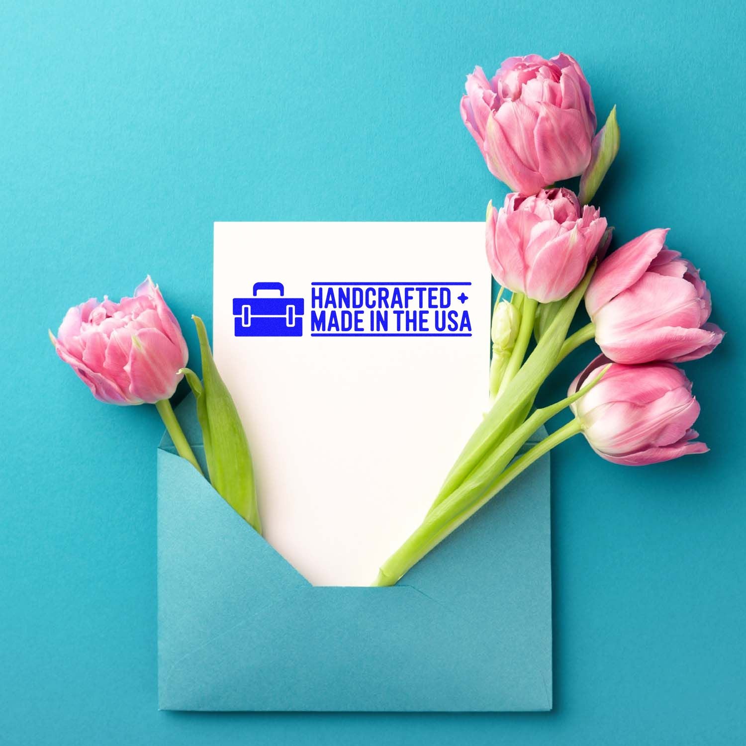 Handcrafted Made in the USA rubber stamp for greeting cards, shown on a blue envelope with pink tulips.