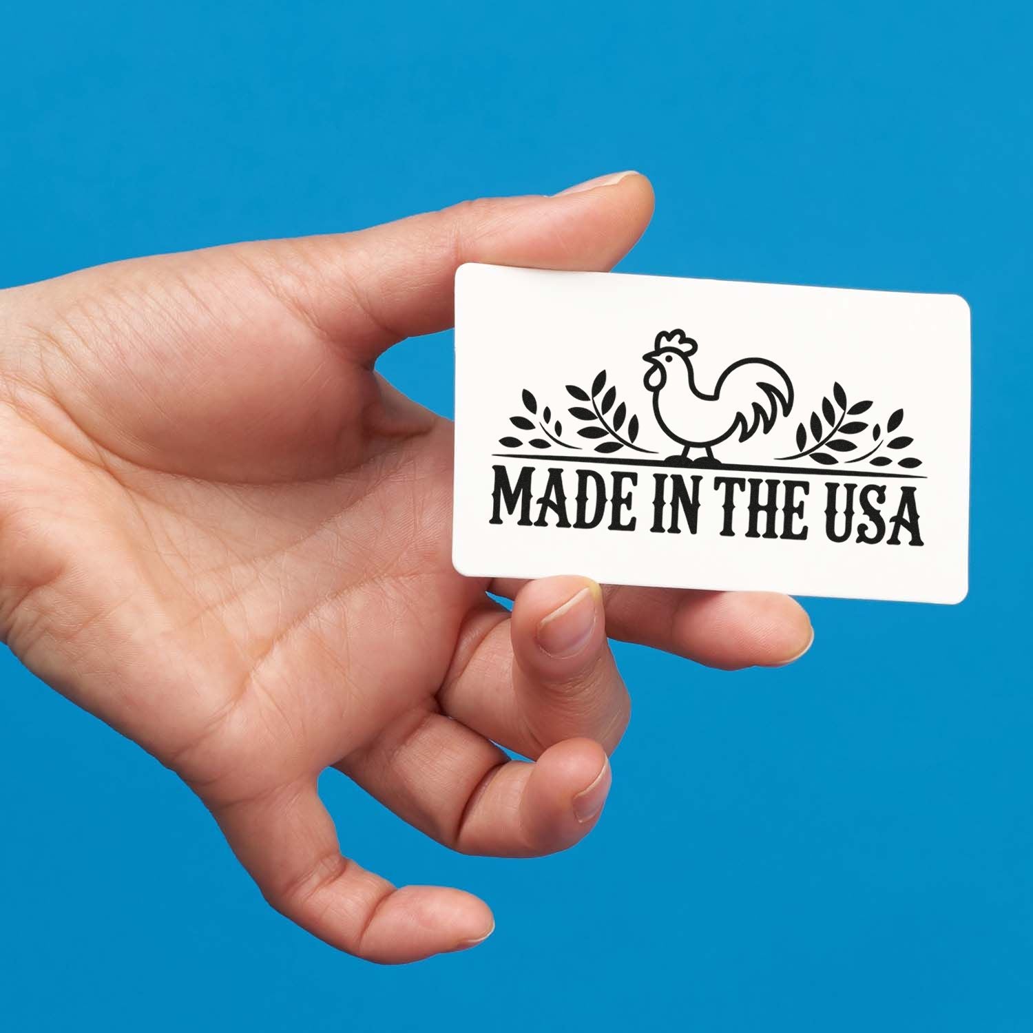 Hand holding a custom rubber stamp featuring a Made in the USA rooster design for product branding.