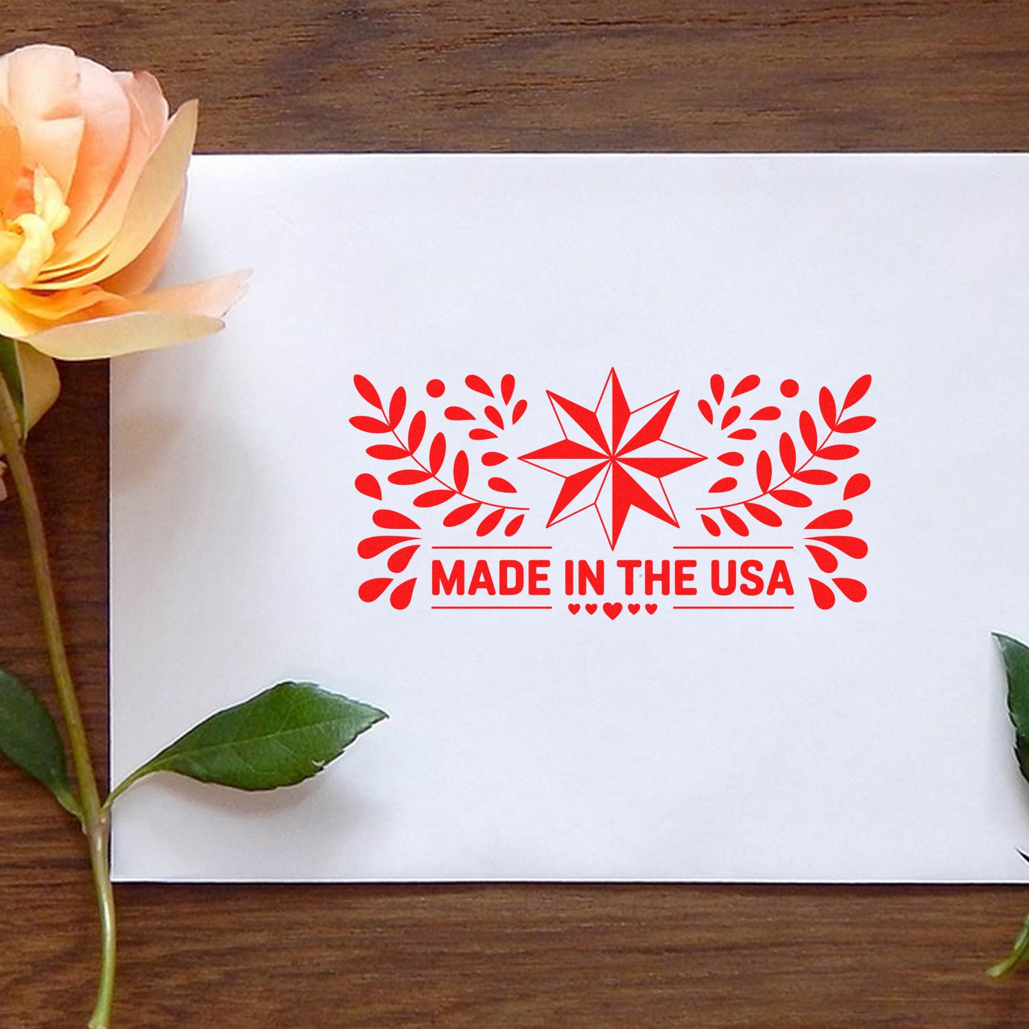 Red Made in the USA rubber stamp impression with star and floral leaves on white paper for patriotic crafts and packaging.