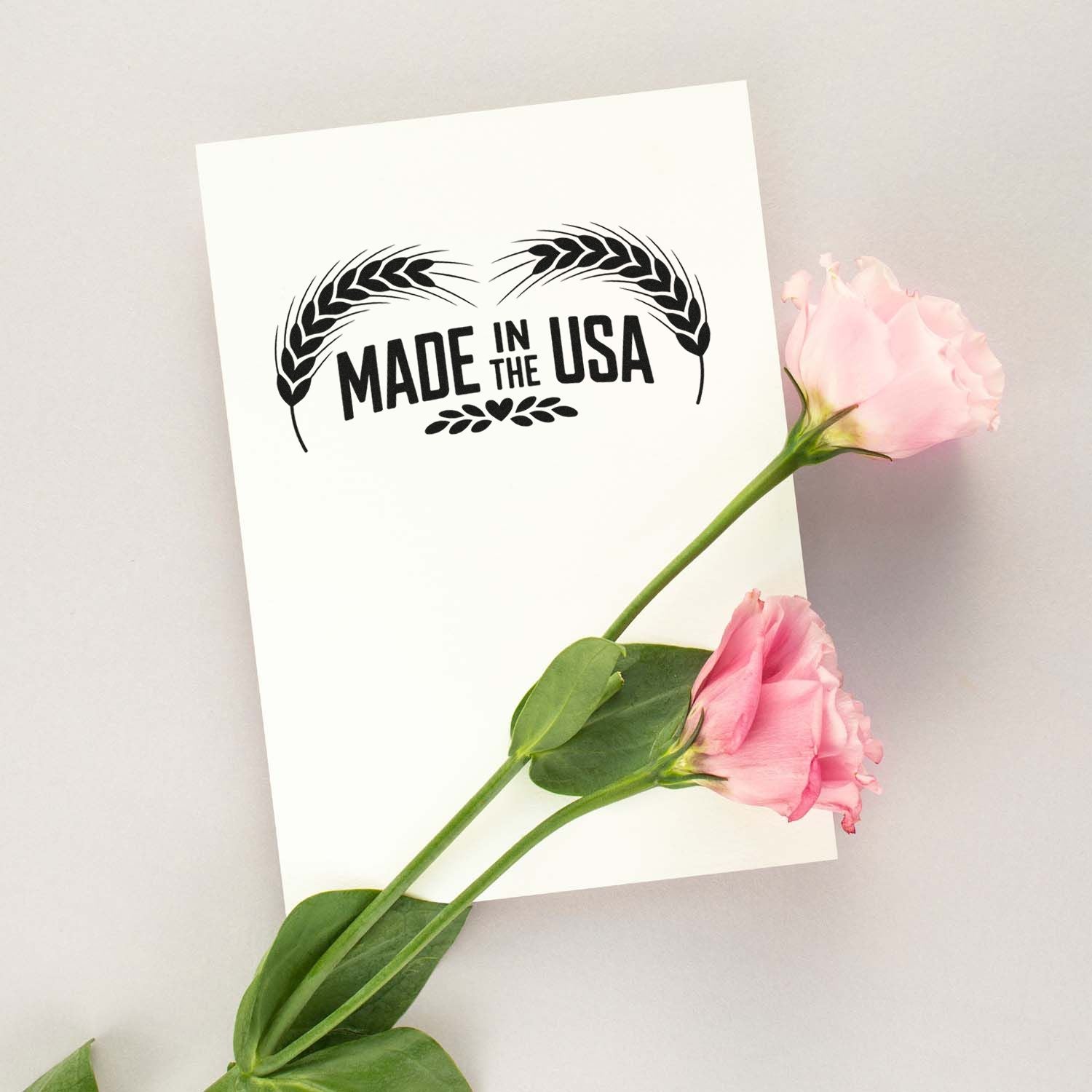 Made in the USA rubber stamp design with wheat motif, displayed on white card and pink flowers for patriotic branding.