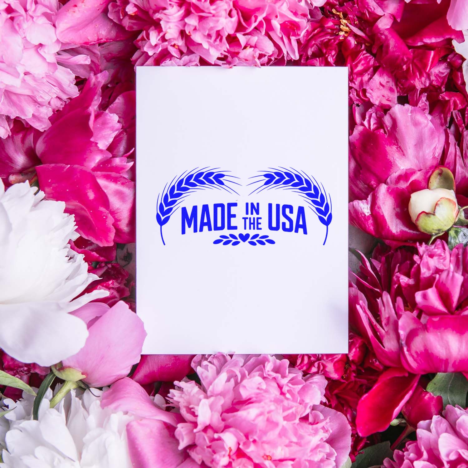 Made in the USA rubber stamp design on a white card, surrounded by pink flowers, ideal for patriotic packaging and branding.