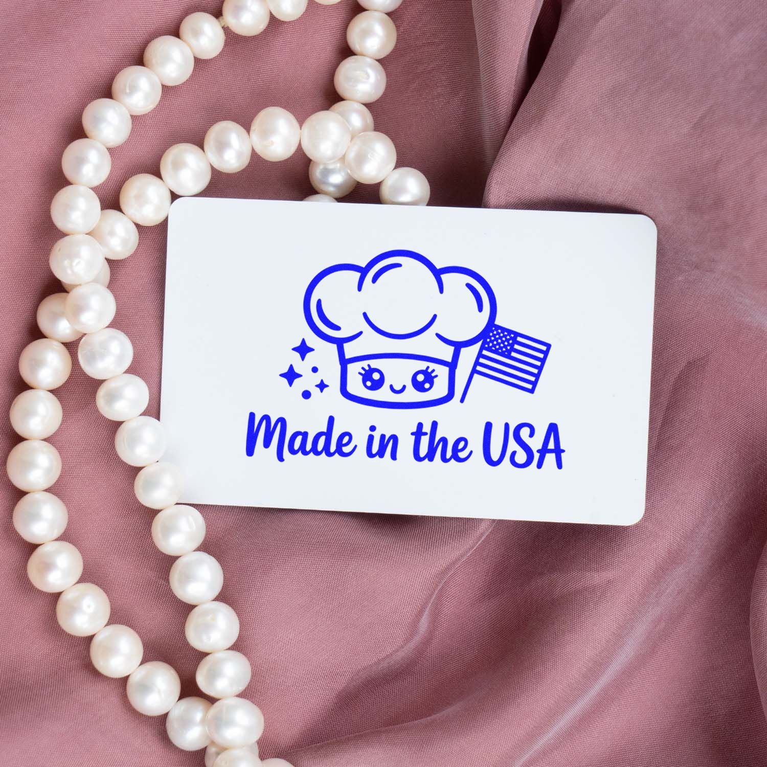 Custom Made in the USA rubber stamp with chef icon, shown on pink fabric with pearl necklace.