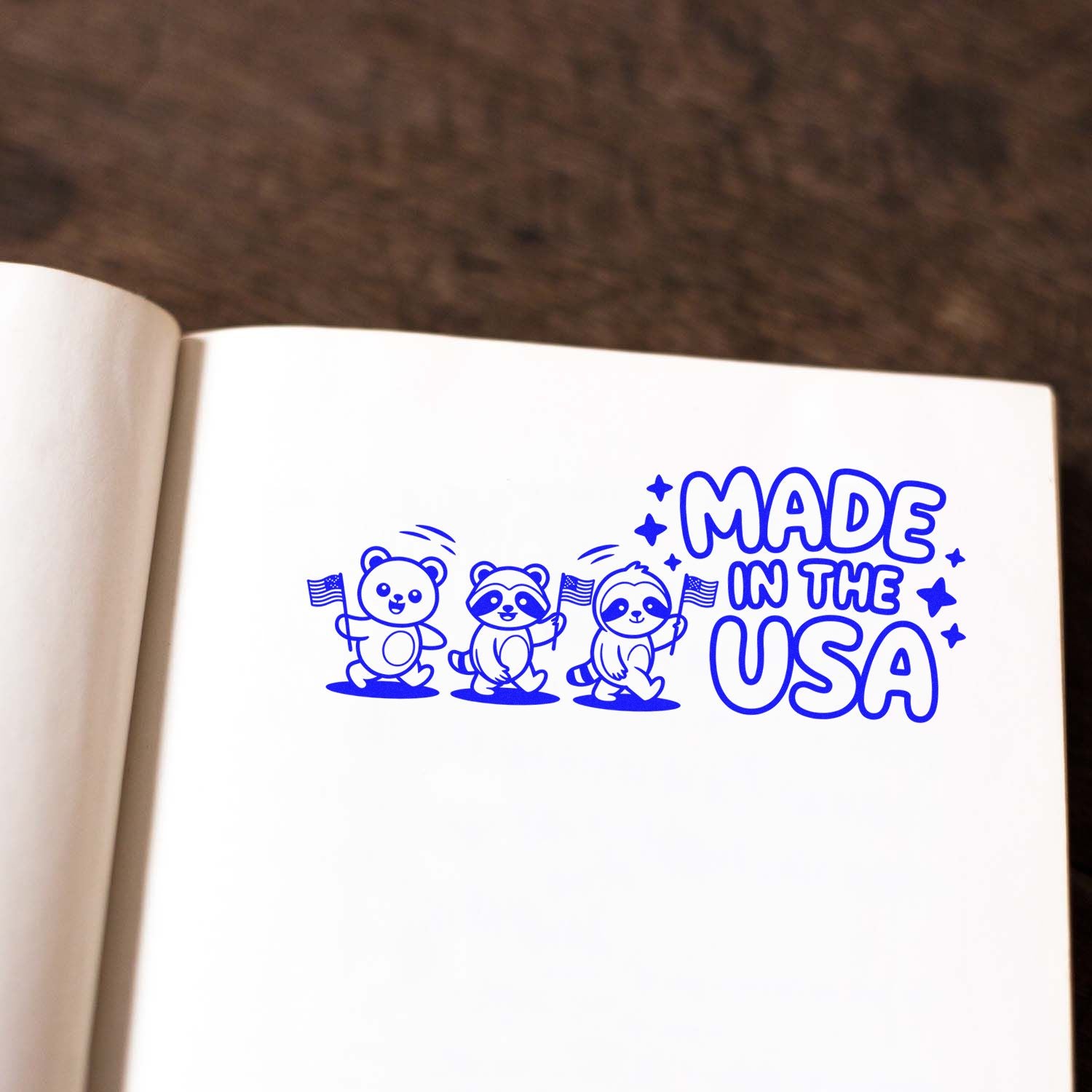 Made in the USA rubber stamp with cartoon bear, raccoon and sloth holding flags, stamped in blue on notebook paper.