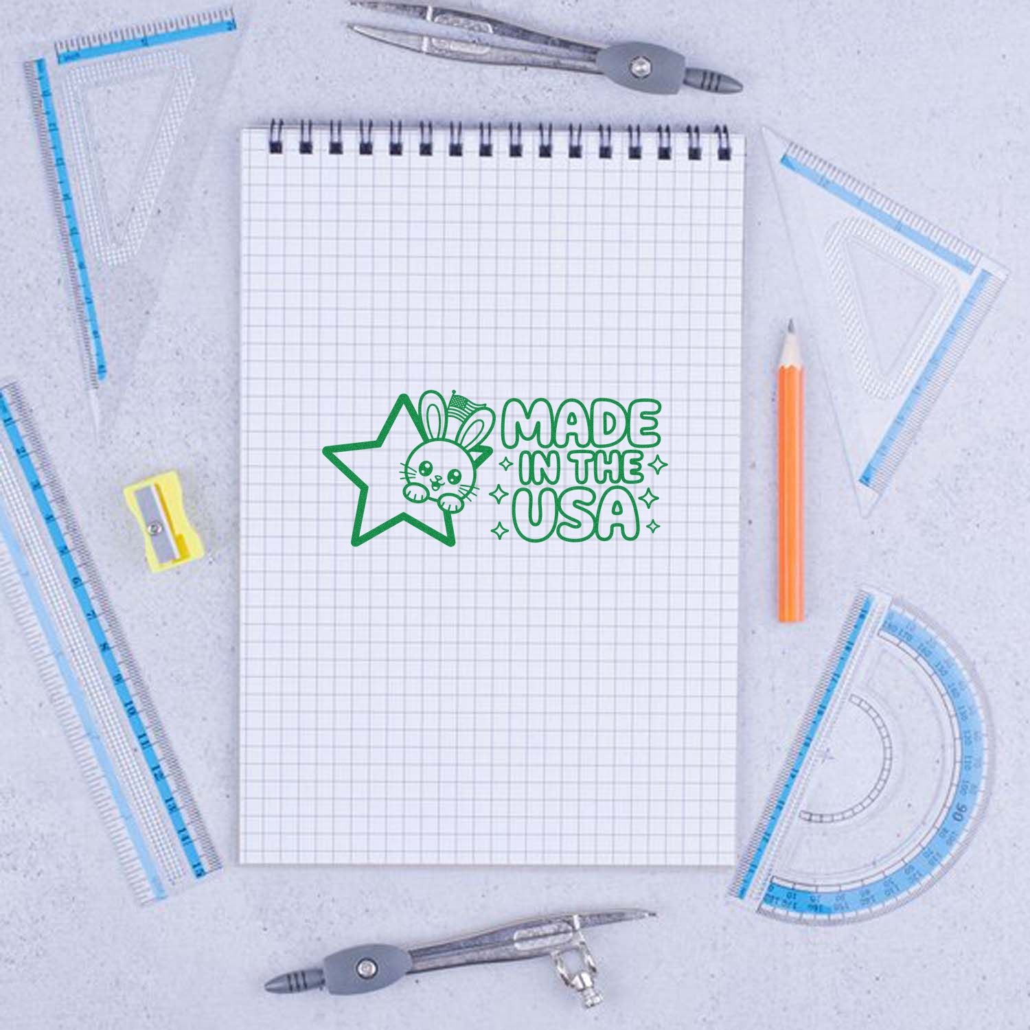 Made in the USA custom rubber stamp design with bunny star logo on notebook, surrounded by drafting tools.