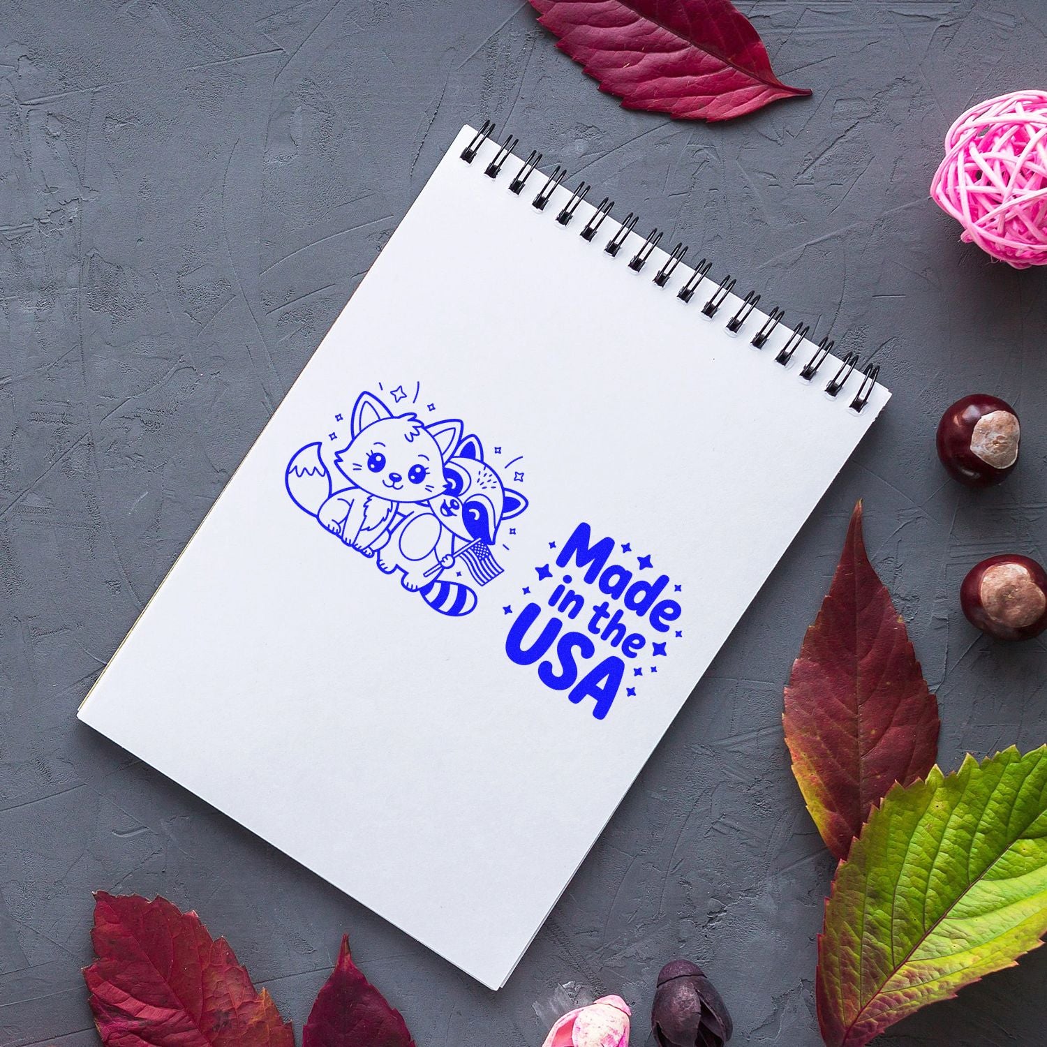 Made in the USA rubber stamp on a spiral notebook, featuring a cute fox and bird for custom craft branding.