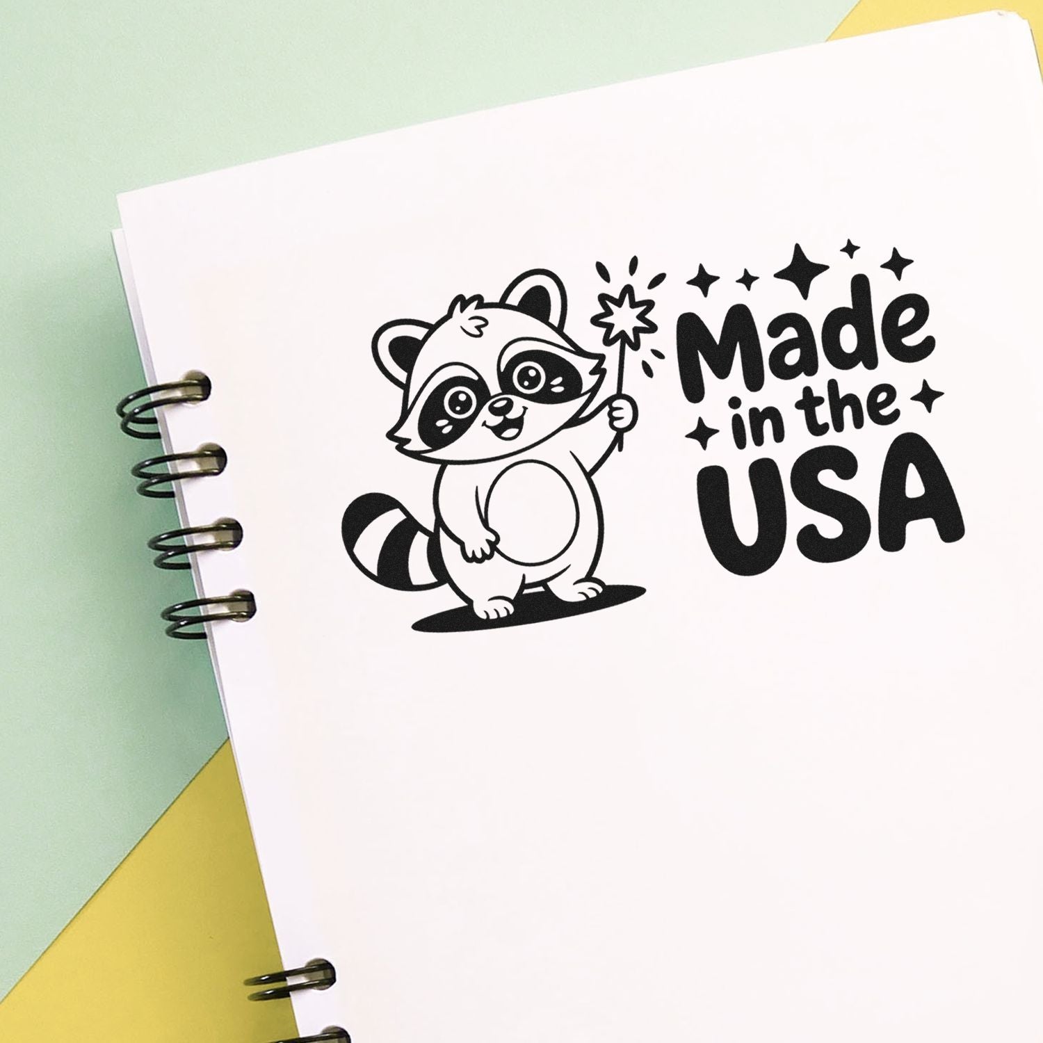 Cute raccoon rubber stamp design with Made in the USA text on notebook page for patriotic crafts, packaging, and branding.