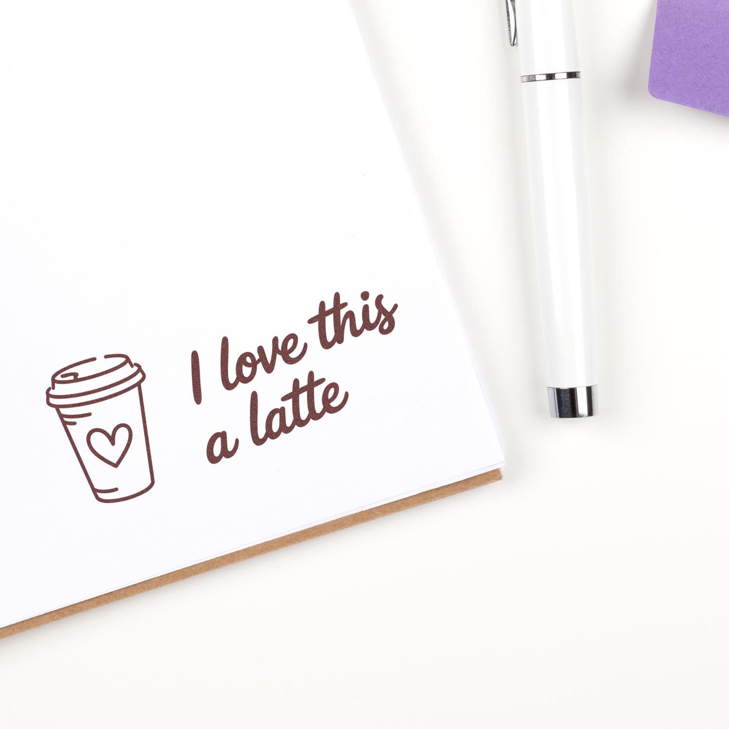 Coffee rubber stamp design with I love this a latte quote, cup icon, and white pen on a notebook.