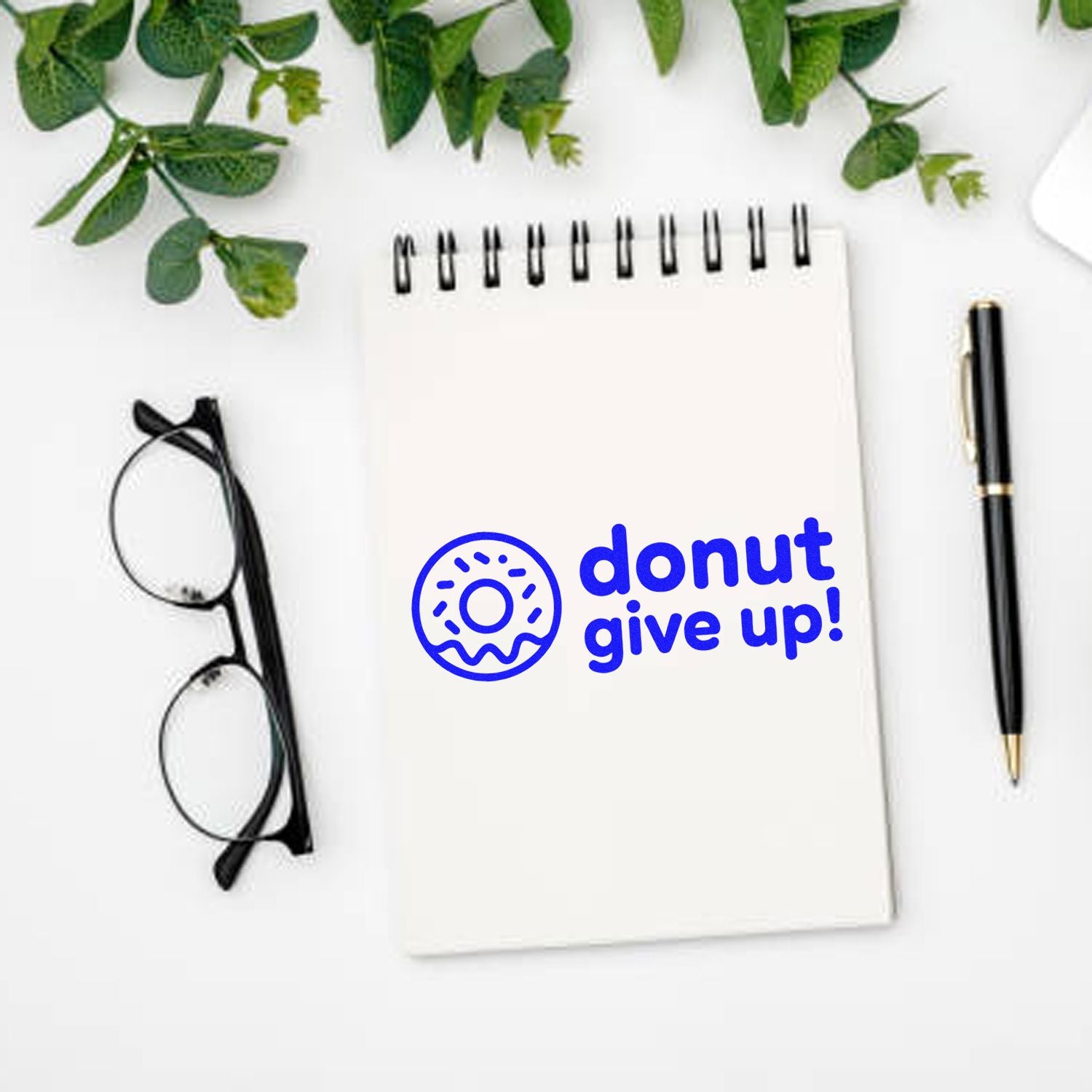 Donut give up motivational rubber stamp on a notebook, playful donut pun for teacher, office, and craft projects.