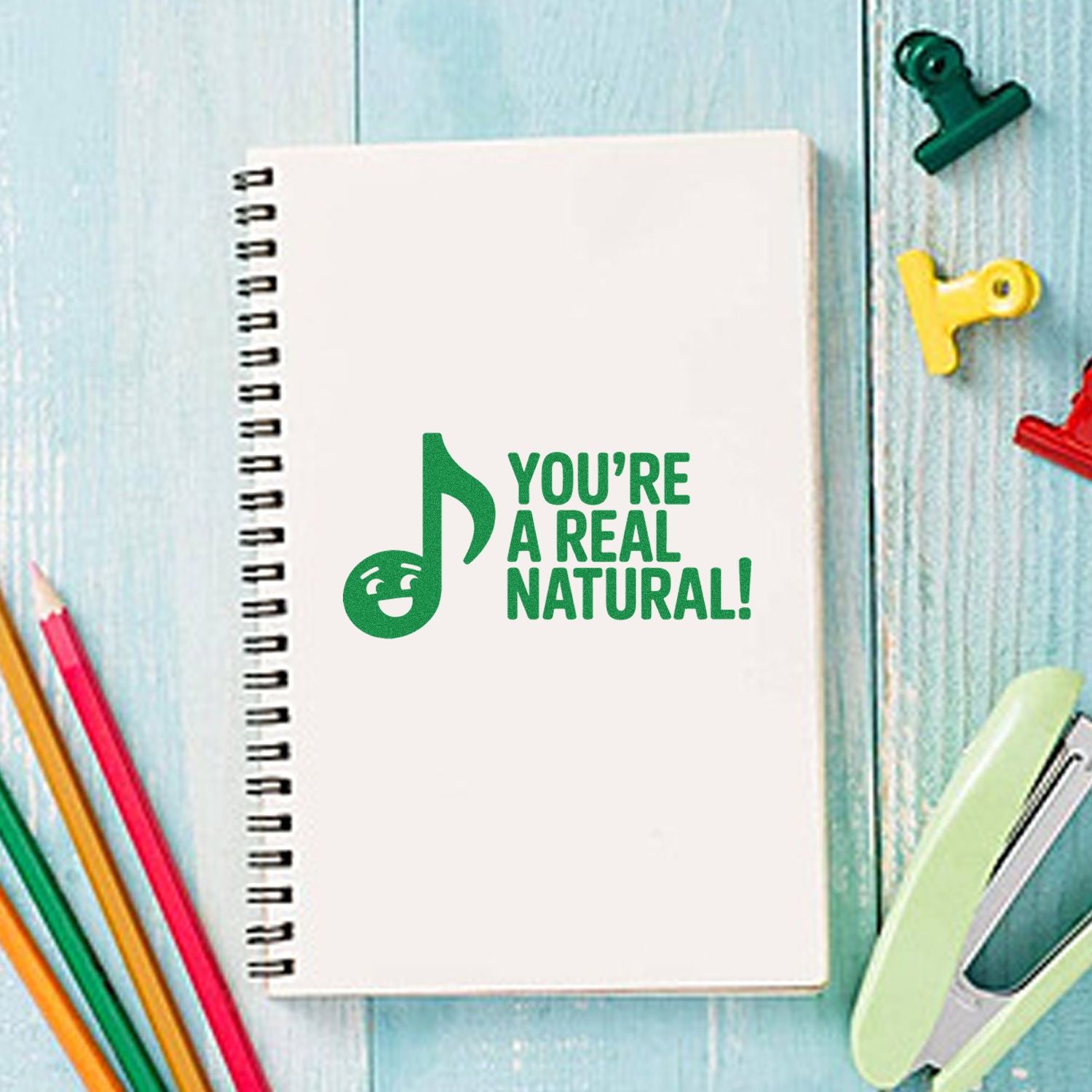 Green rubber stamp reading Youre a real natural! on a notebook, perfect for fun encouragement and classroom use.