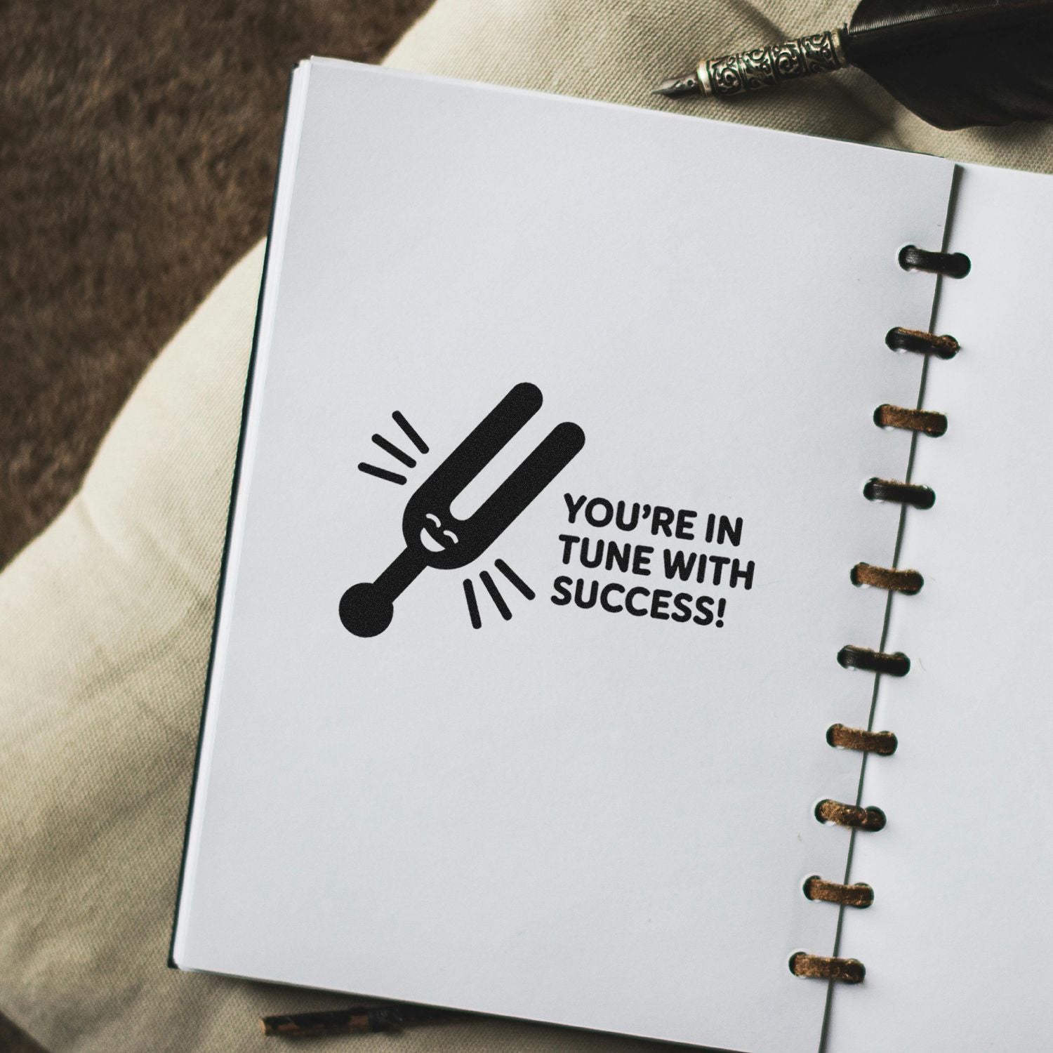 Custom rubber stamp with tuning fork and Youre in Tune With Success! motivational message on a notebook page