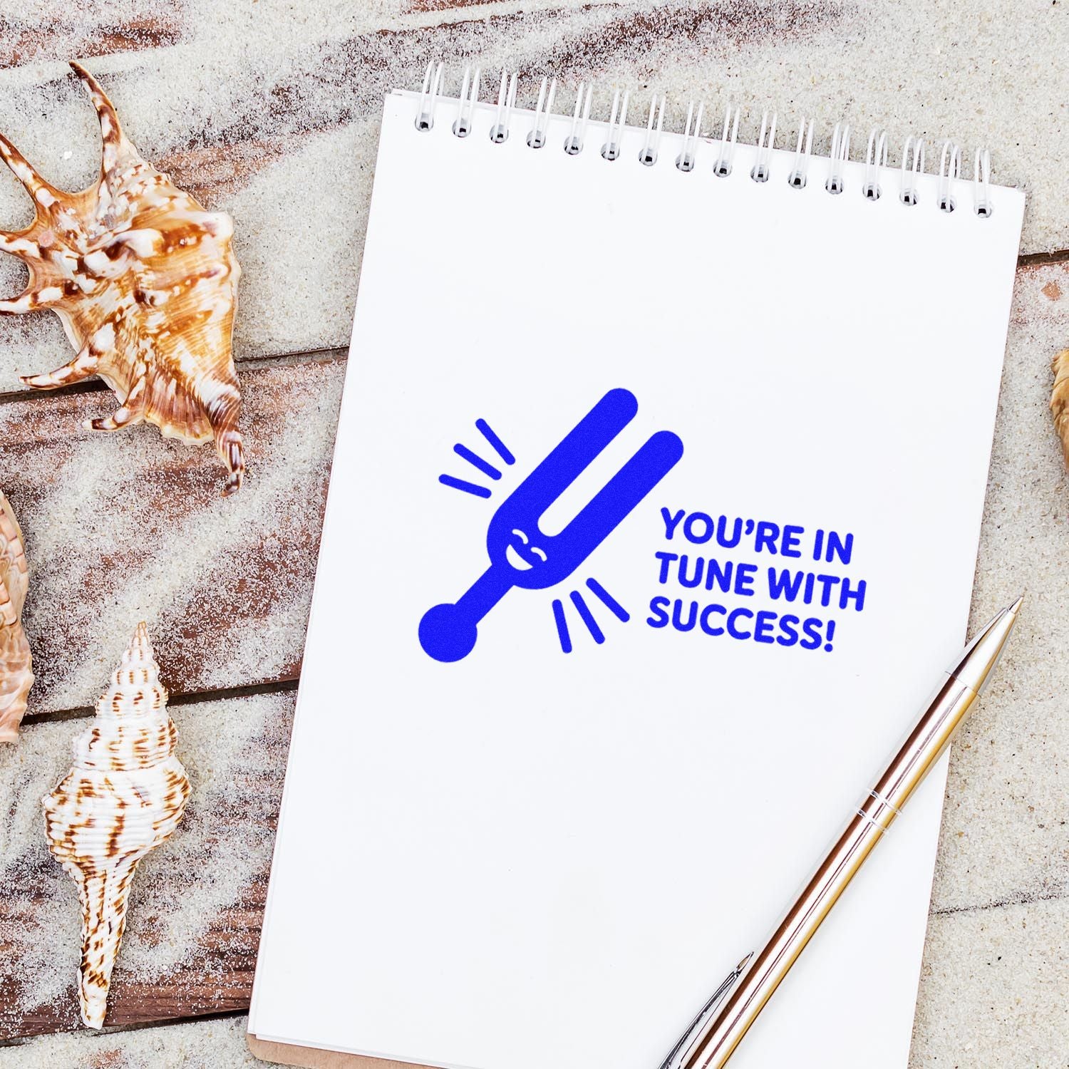 Motivational rubber stamp impression reading Youre in tune with success! with tuning fork icon on a notebook.