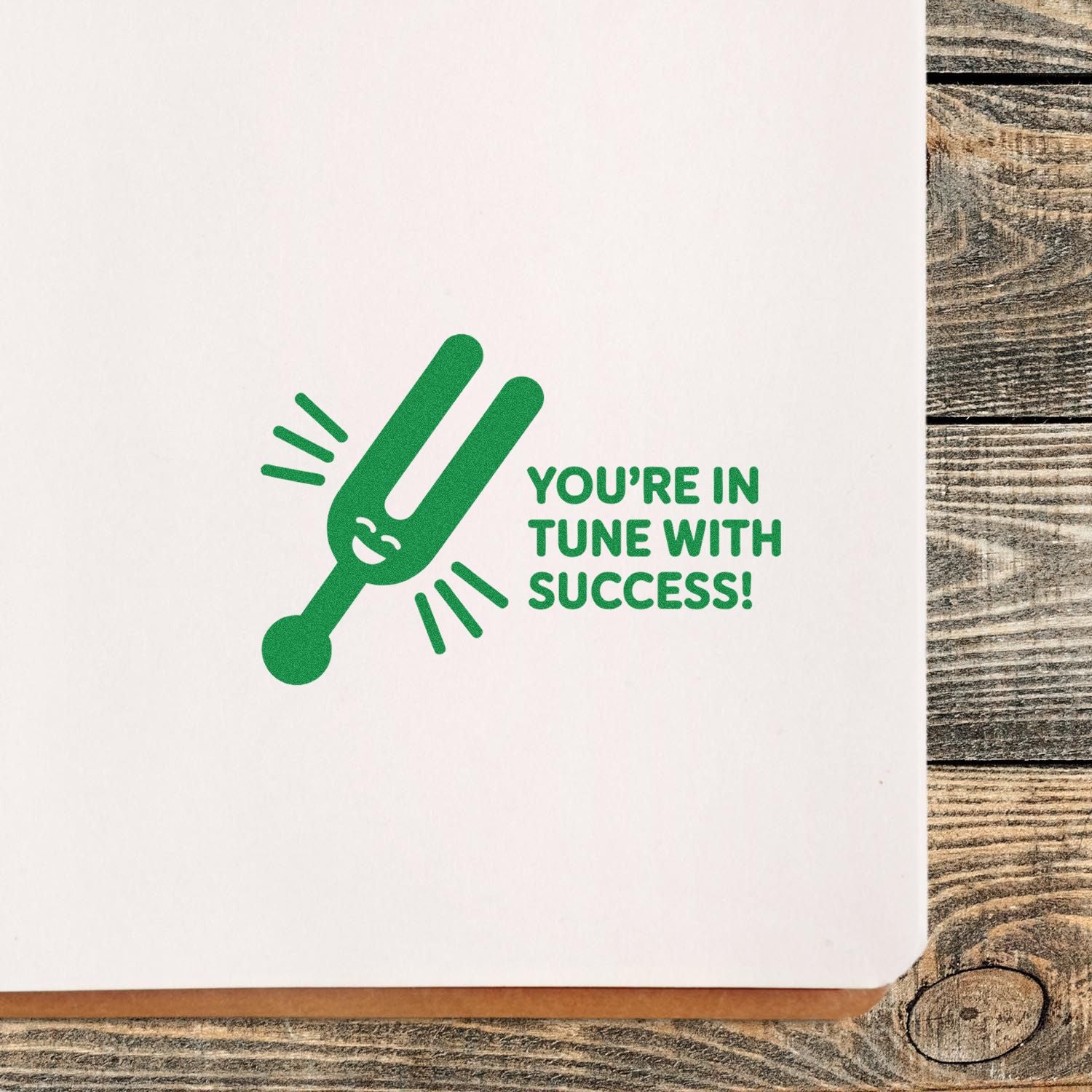 Motivational custom rubber stamp with green tuning fork and Youre in tune with success! on white paper.