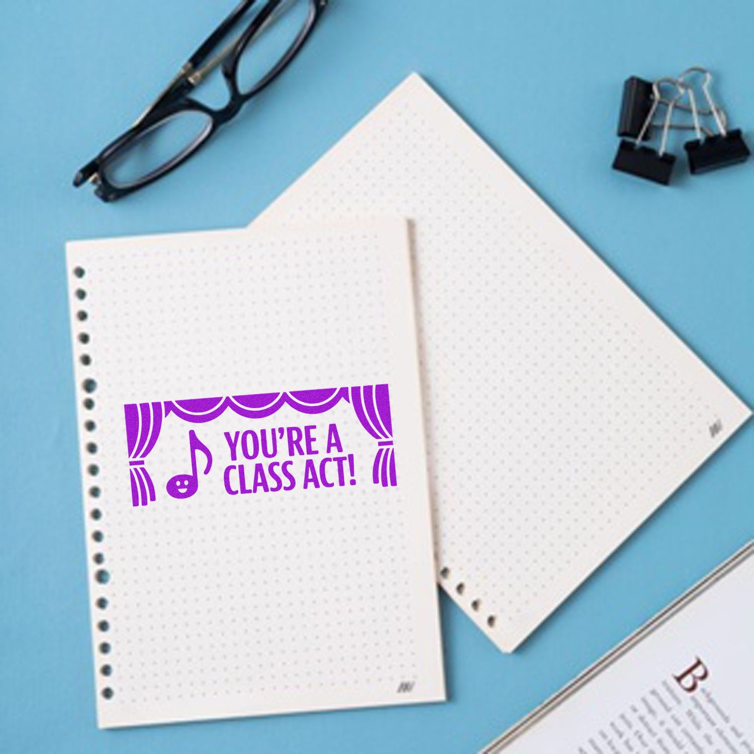 Purple rubber stamp reading Youre a Class Act! on notebook paper, ideal for teacher appreciation and classroom rewards.