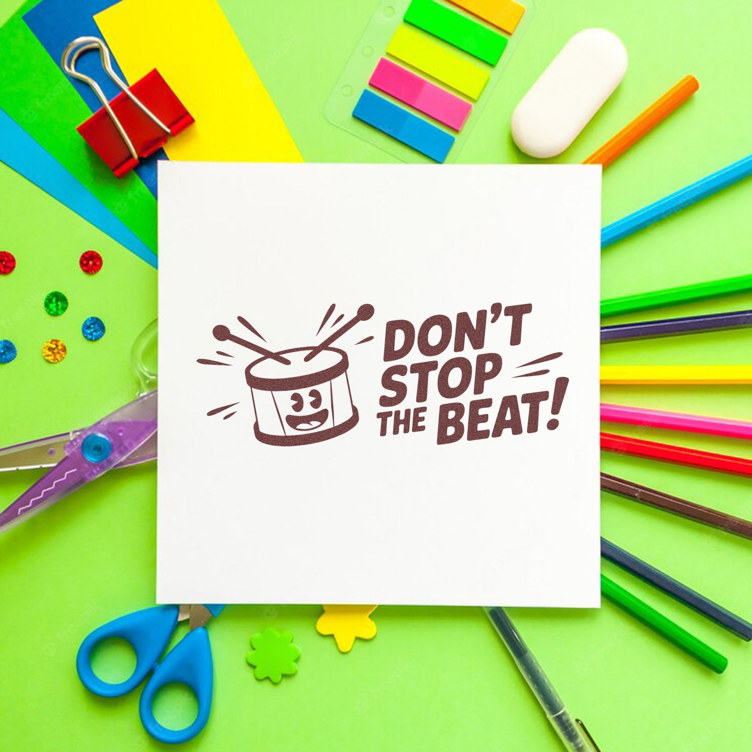 Don't Stop the Beat rubber stamp design with drum icon, shown on a white card surrounded by colorful school supplies.