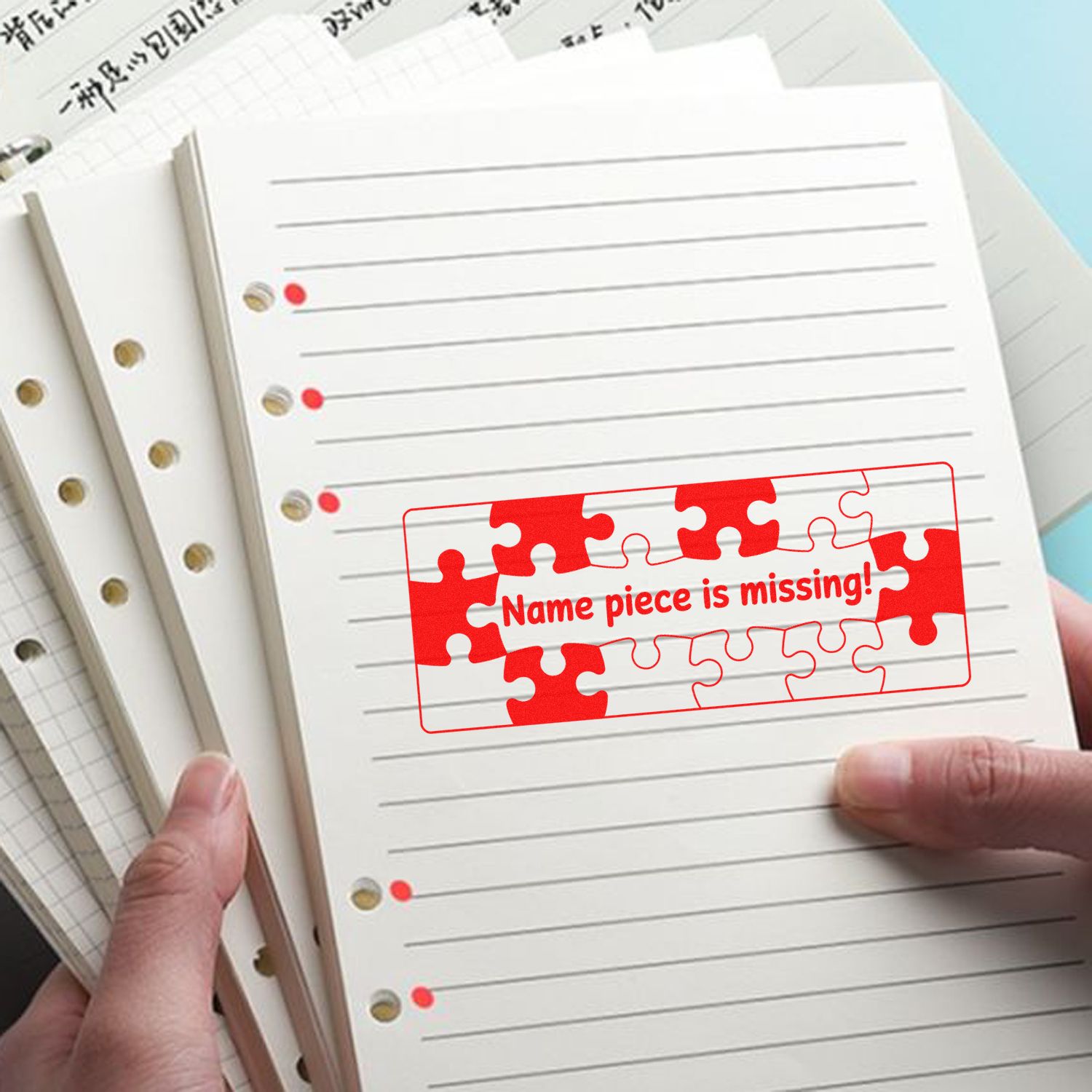 Custom rubber stamp for school notebooks, marking missing name on lined paper with a red puzzle design.