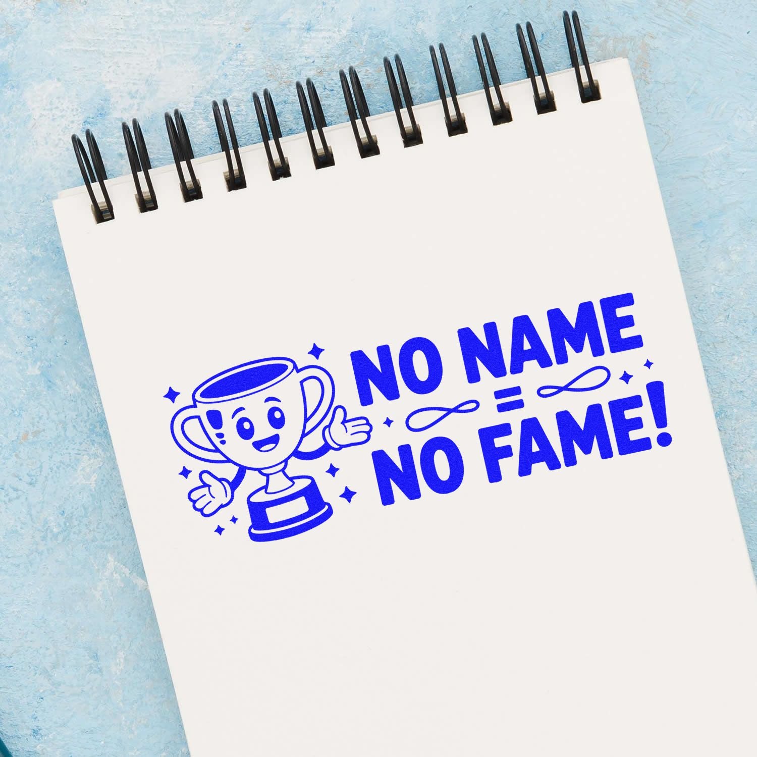 Custom rubber stamp design with trophy mascot and "No Name No Fame" slogan on a spiral notebook.
